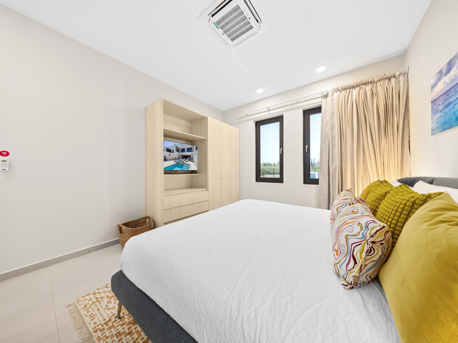 Retreat to serenity in tranquil bedroom of the apartment in Noord Aruba - King size bed with soft hues and plush bedding promise a restful night's sleep - With flat screen smart TV providing entertainment center for movie nights or relaxation