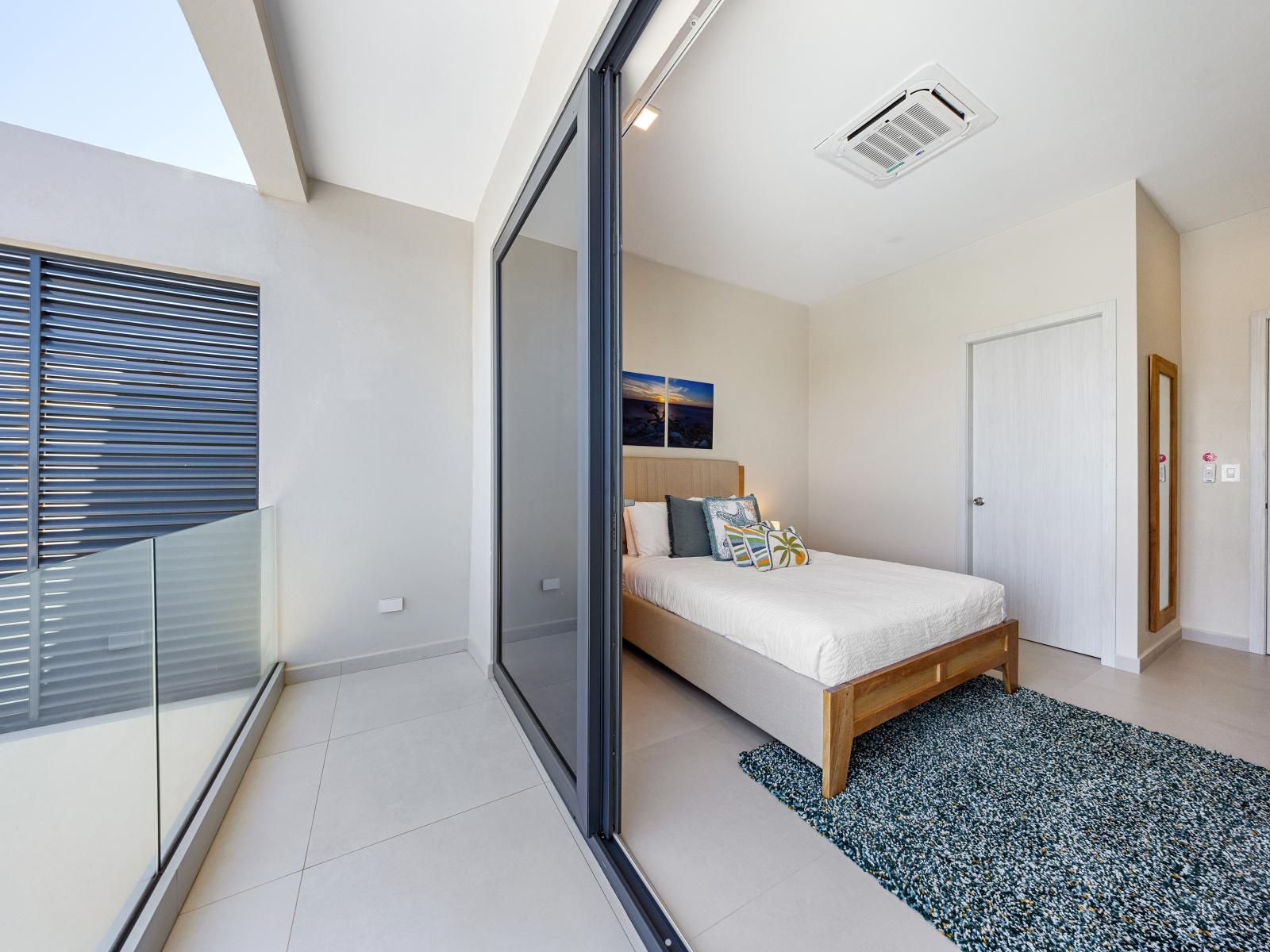 Escape to relaxation in inviting bedroom sanctuary of the apartment in Noord Aruba - Features a balcony, an attached bathroom and a modern full length mirror - Bedroom with a cozy ambiance, blending comfort and aesthetics