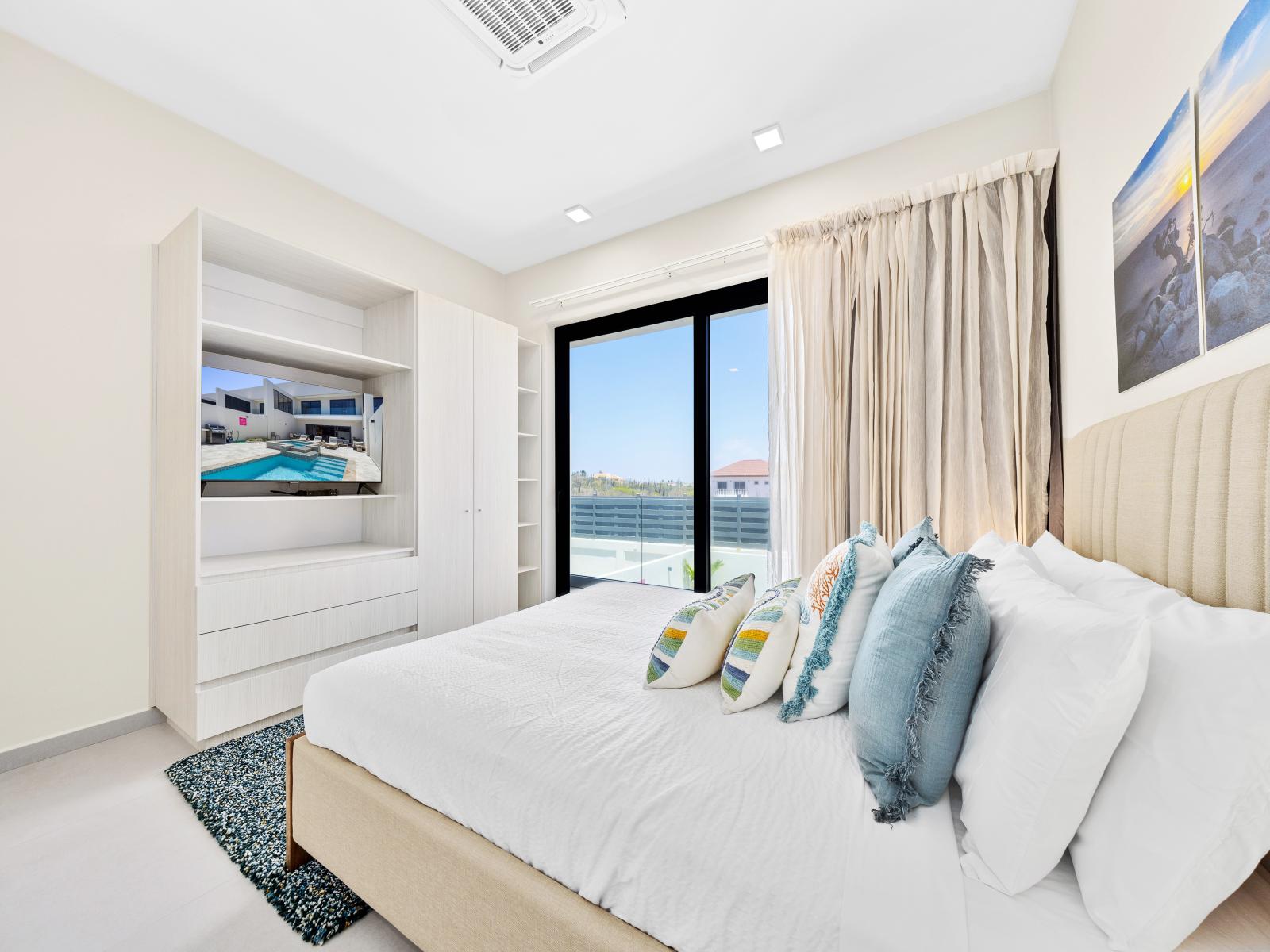 Savor moments of tranquility in serene bedroom of the apartment in Noord Aruba - Where minimalist design and cozy accents foster a sense of calm - Enjoy your favorite show on the smart TV or experience peace in the balcony of the bedroom