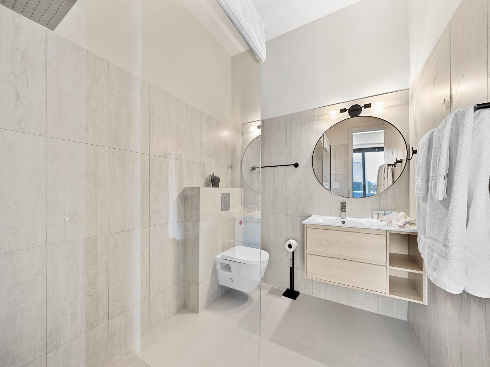 Experience the pinnacle of comfort in modern bathroom of the apartment in Noord Aruba - Featuring a spacious walk-in shower area and modern fixtures for ultimate relaxation - Plenty of light highlights the elegant tilework adorning the space