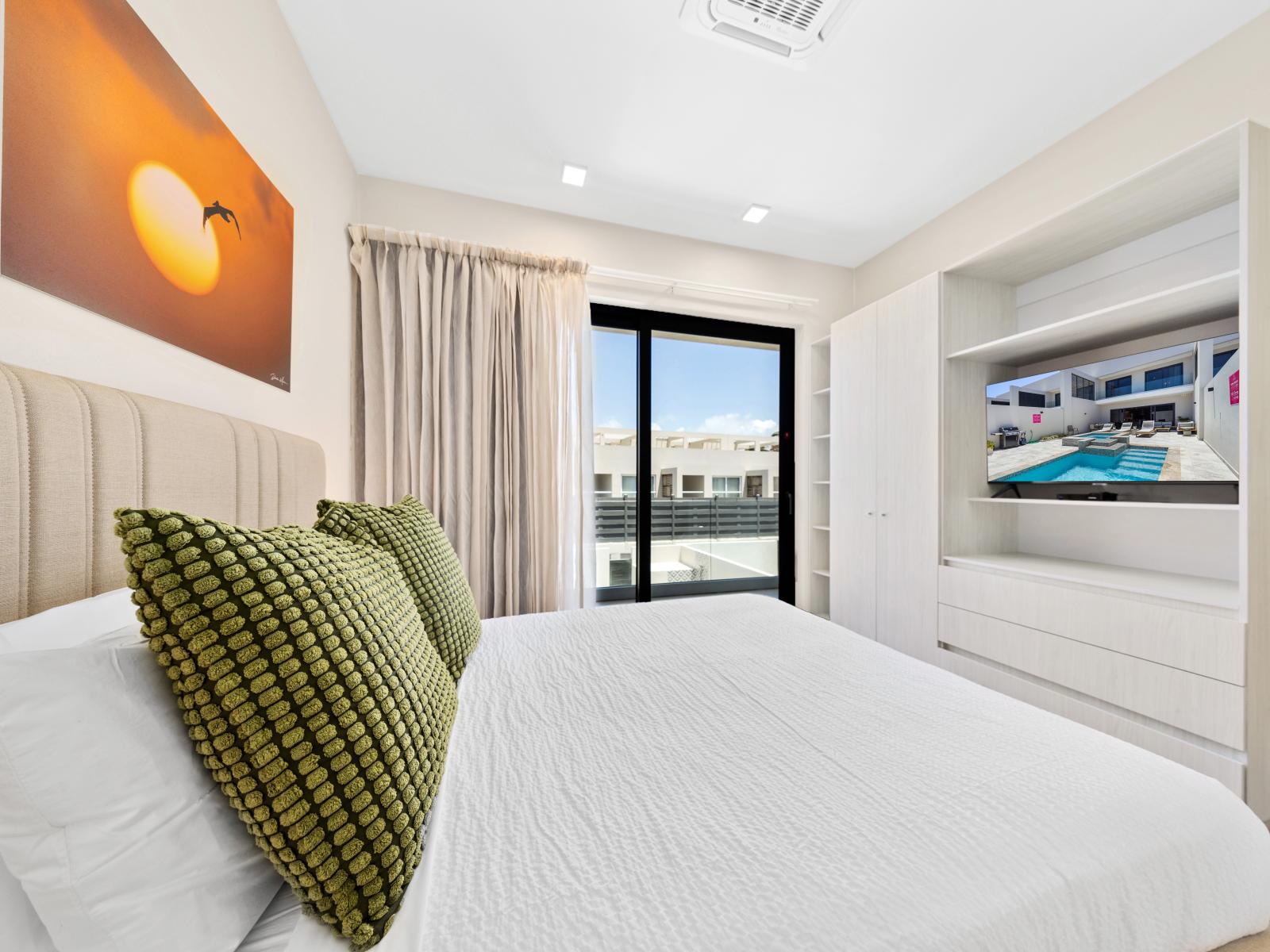 Unwind in style in chic bedroom retreat of the apartment in Noord Aruba - Offers a flat screen smart TV and access to balcony - Relax in sophisticated bedroom, where sleek furnishings and subdued lighting set the stage for restful slumber