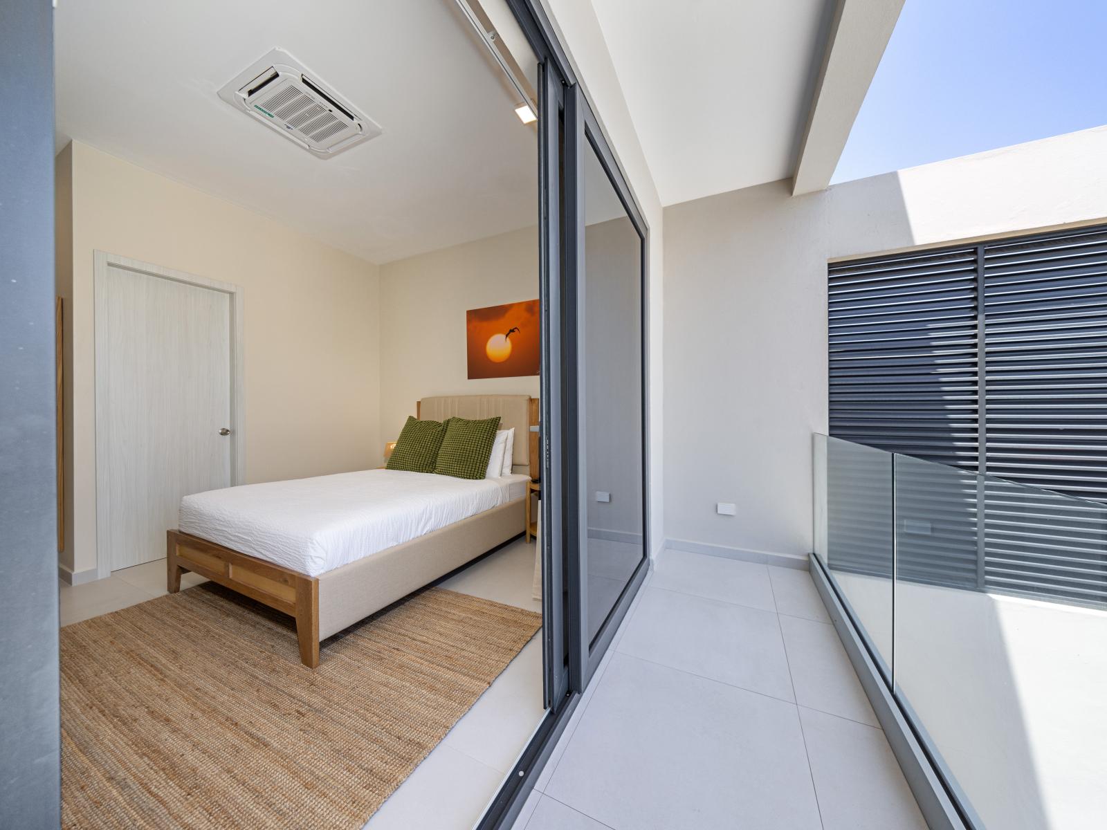 Enjoy a peaceful night's rest in stylish bedroom of the apartment in Noord Aruba - A balcony which you can reach through the glass sliding doors - Modern design elements and thoughtful touches ensure a comfortable stay