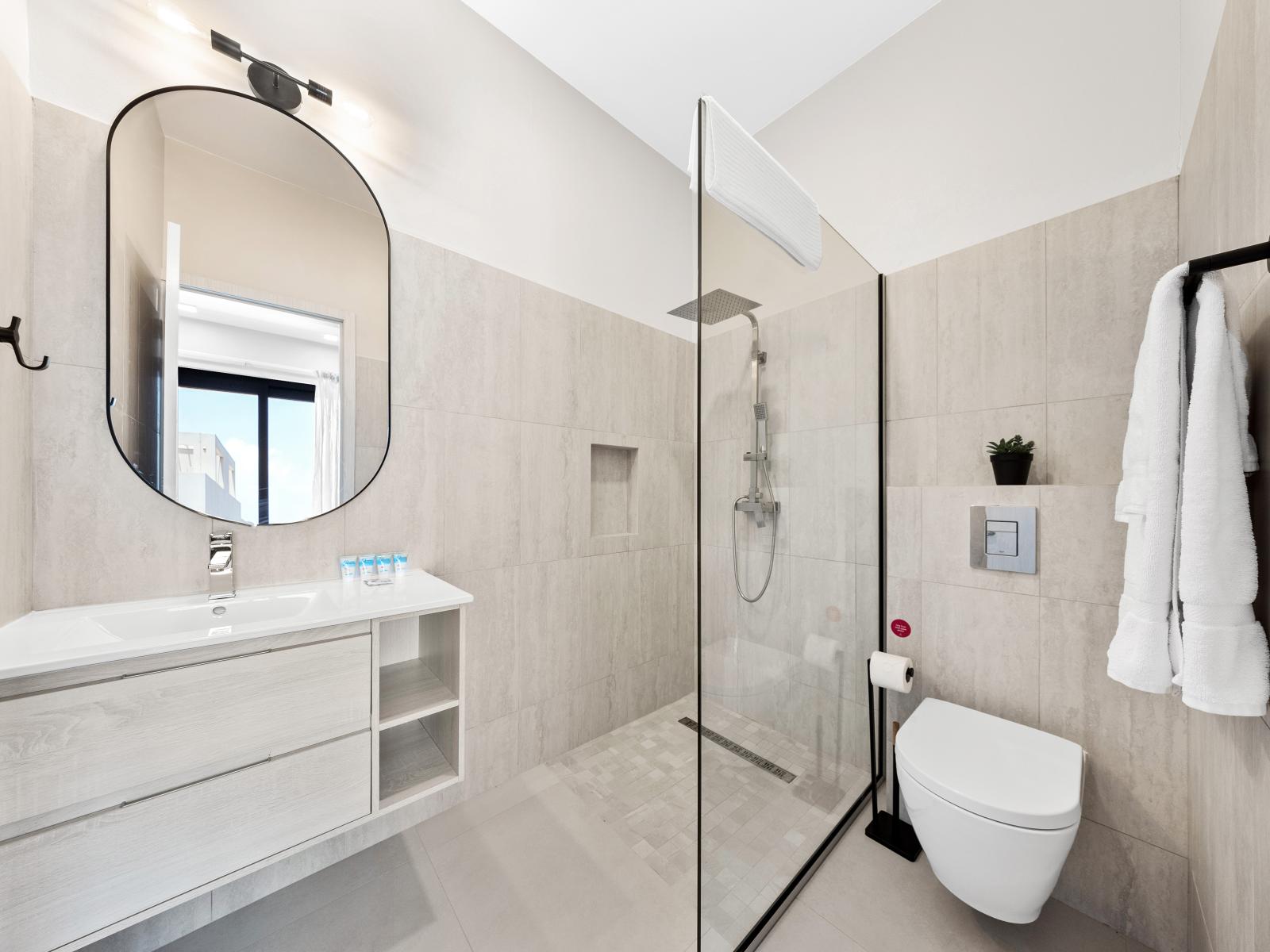 Escape to luxury in stylish bathroom retreat of the apartment in Noord Aruba - Boasting a spacious walk-in shower, sleek vanity area and quality toiletries for a decadent experience - Clean lines and refined details for a sophisticated look