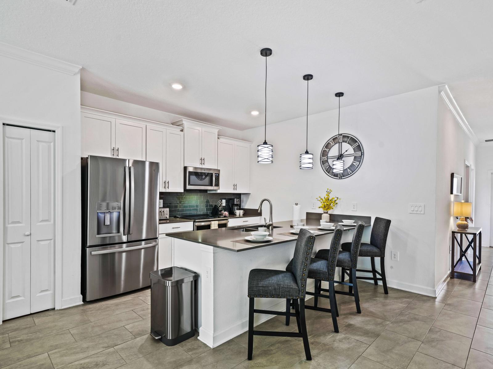 Create unforgettable meals in a sleek yet functional kitchen of the townhouse in Davenport Florida - Coordinated color palette for a cohesive look, backsplash adding a touch of personality - Breakfast bar and high chairs for casual dining