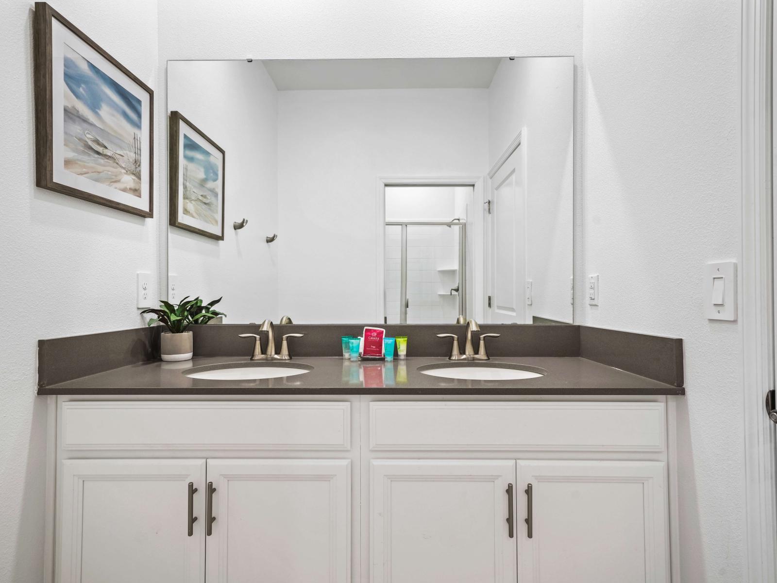 Refresh and rejuvenate in spa-like bathroom of the townhouse in Davenport Florida - Sophisticated color palette creating a serene ambiance and a chic dual vanity - Tastefully decored with potted plants and wall painting