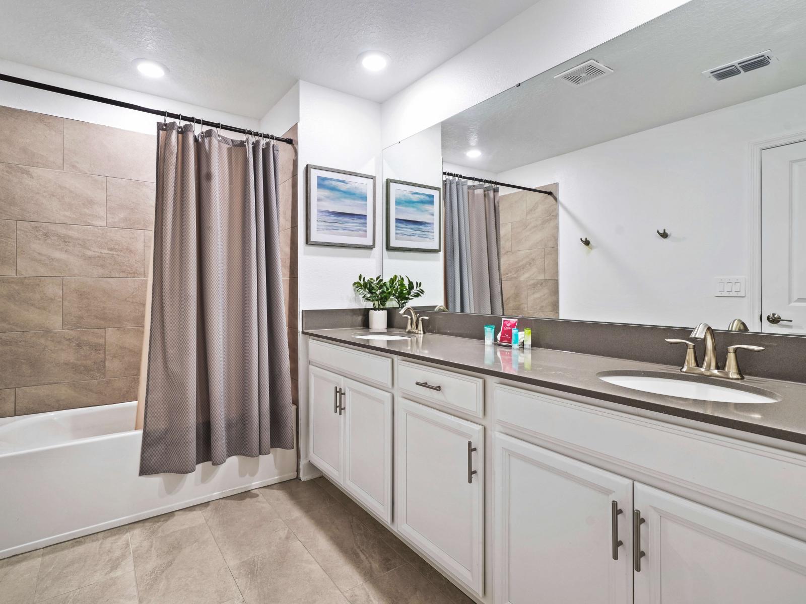 Unwind and escape to tranquility in a beautifully appointed bathroom of the townhouse in Davenport Florida - With a bathtub and a shower combo with large mirror and dual vanity - Attention to detail, from the elegant tiles to the faucets