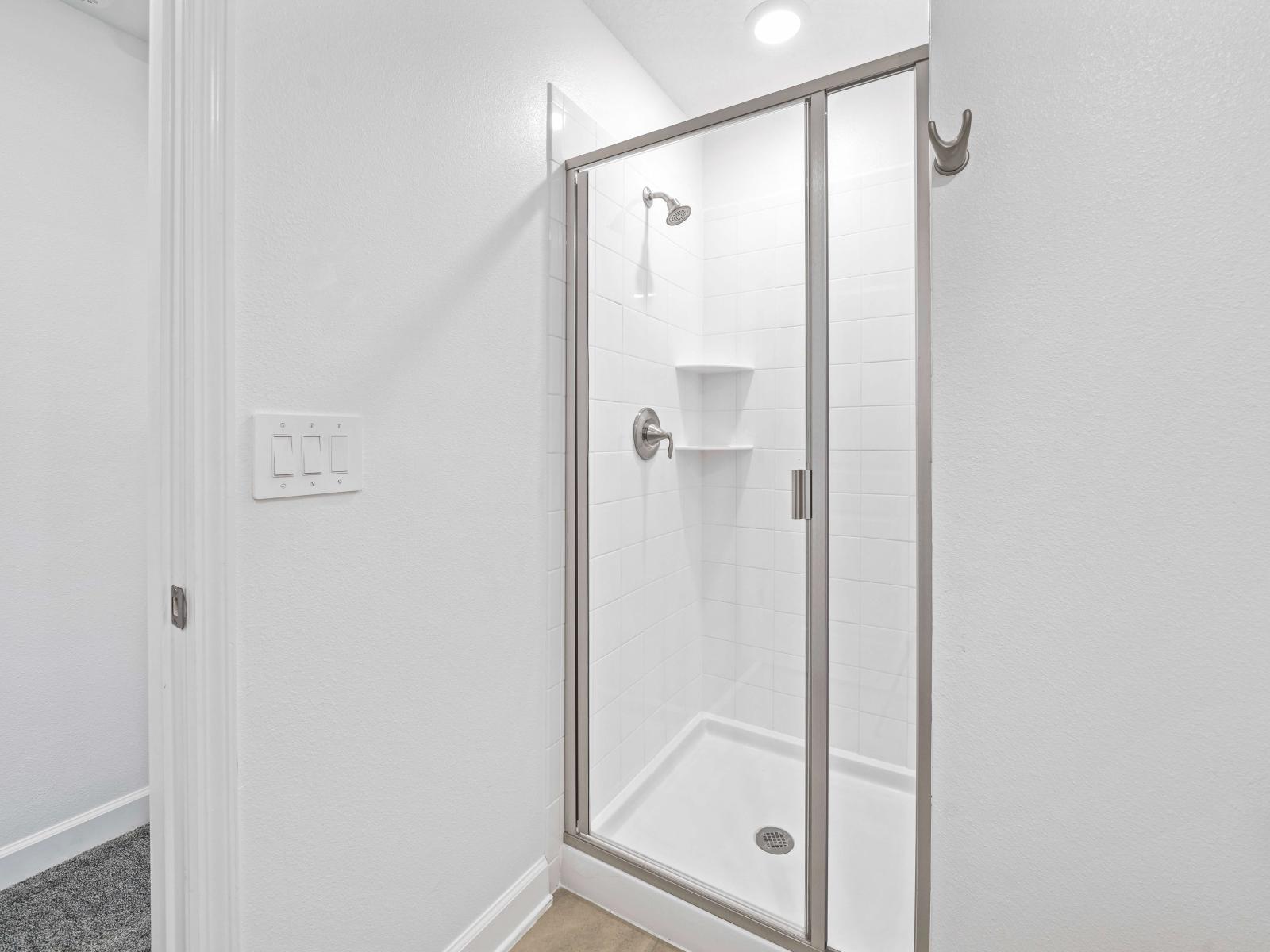 Savor moments of serenity in a pristine bathroom of the townhouse in Davenport Florida - Glass-enclosed spacious walk-in shower stall - Subtle color palette enhancing the overall sense of sophistication