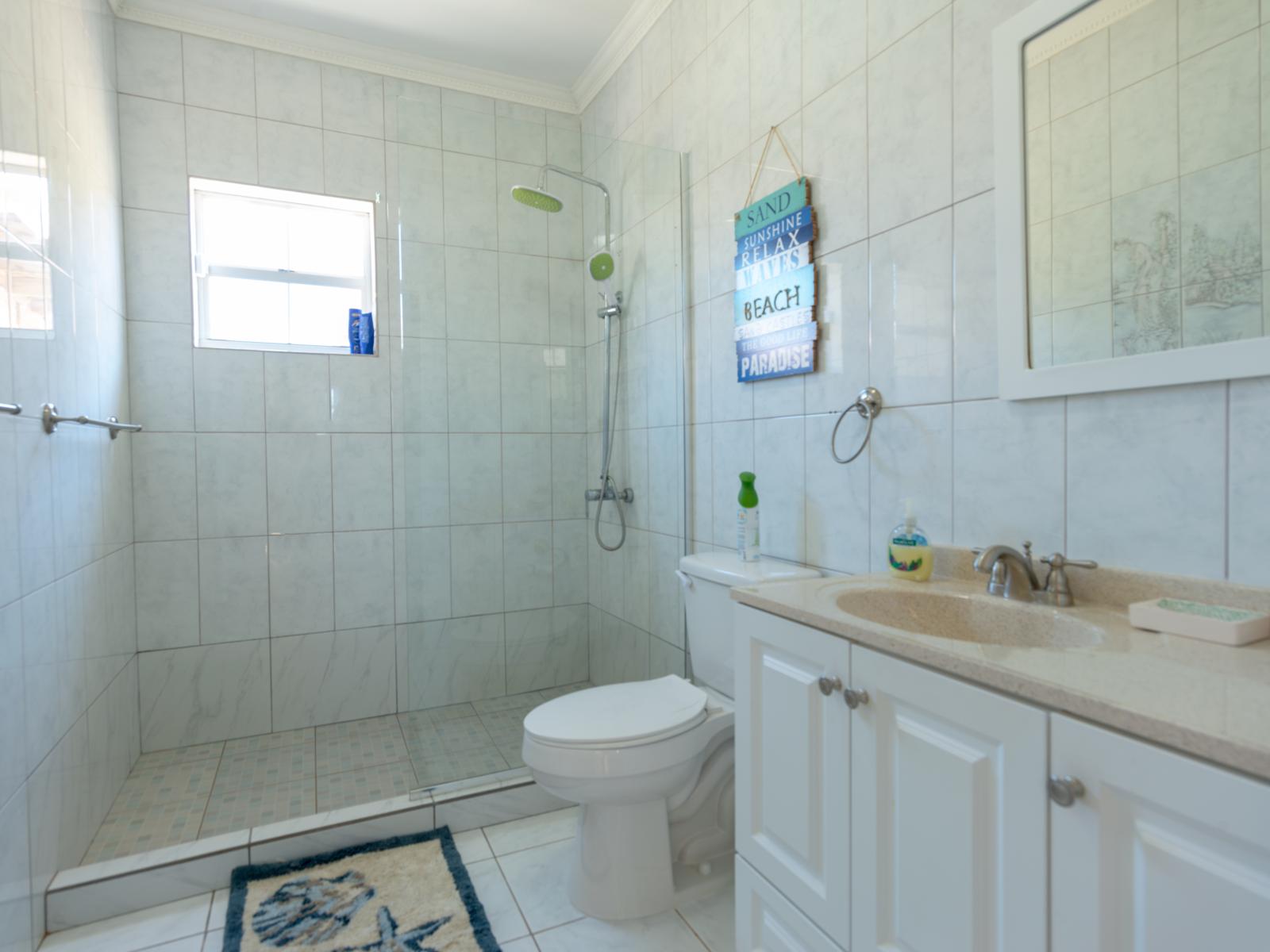 Freshen up and feel rejuvenated in clean and welcoming bathroom of the home in Noord Aruba - Spacious walk-in shower area and bathroom essentials for your convenience - Elegance meets functionality in thoughtfully appointed bathroom