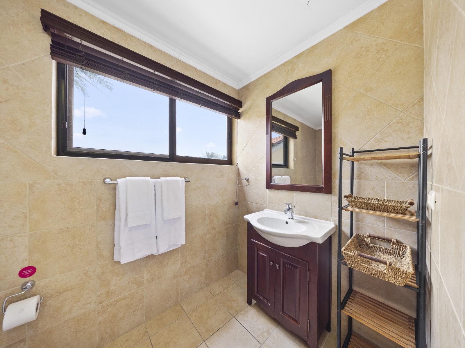 - Indulge in relaxation in meticulously designed bathroom of the townhouse in Noord Aruba - Spa-like experience in lavish bathroom with chic vanity and large mirror - Unwind in style in our bathroom with the availability of all bathroom essentials