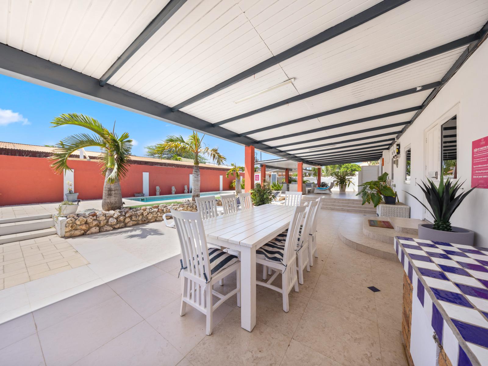 Enjoy charming al fresco dining in our outdoor dining area of the home in Oranjestad, Aruba - Spacious seating arrangement comfortably accommodates all guests for gatherings - The elegant table setup features stylish furniture and chic tableware