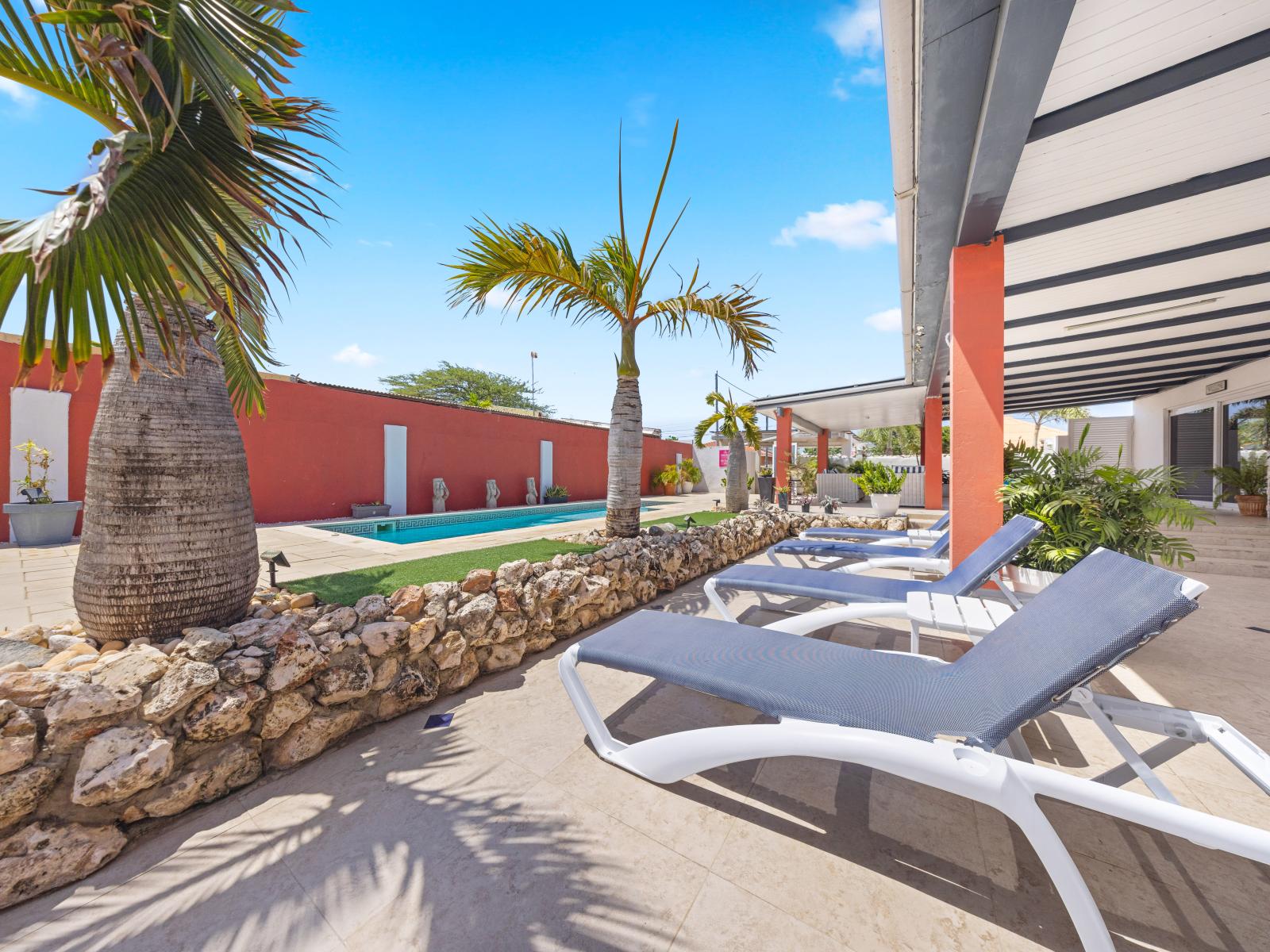 Relax and enjoy a refreshing swim in our pool area of the home in Oranjestad, Aruba - Bask in the sun on our cozy loungers perfect for soaking up the rays - Take a break from the sun under the shaded pergola providing a cool and comfortable retreat