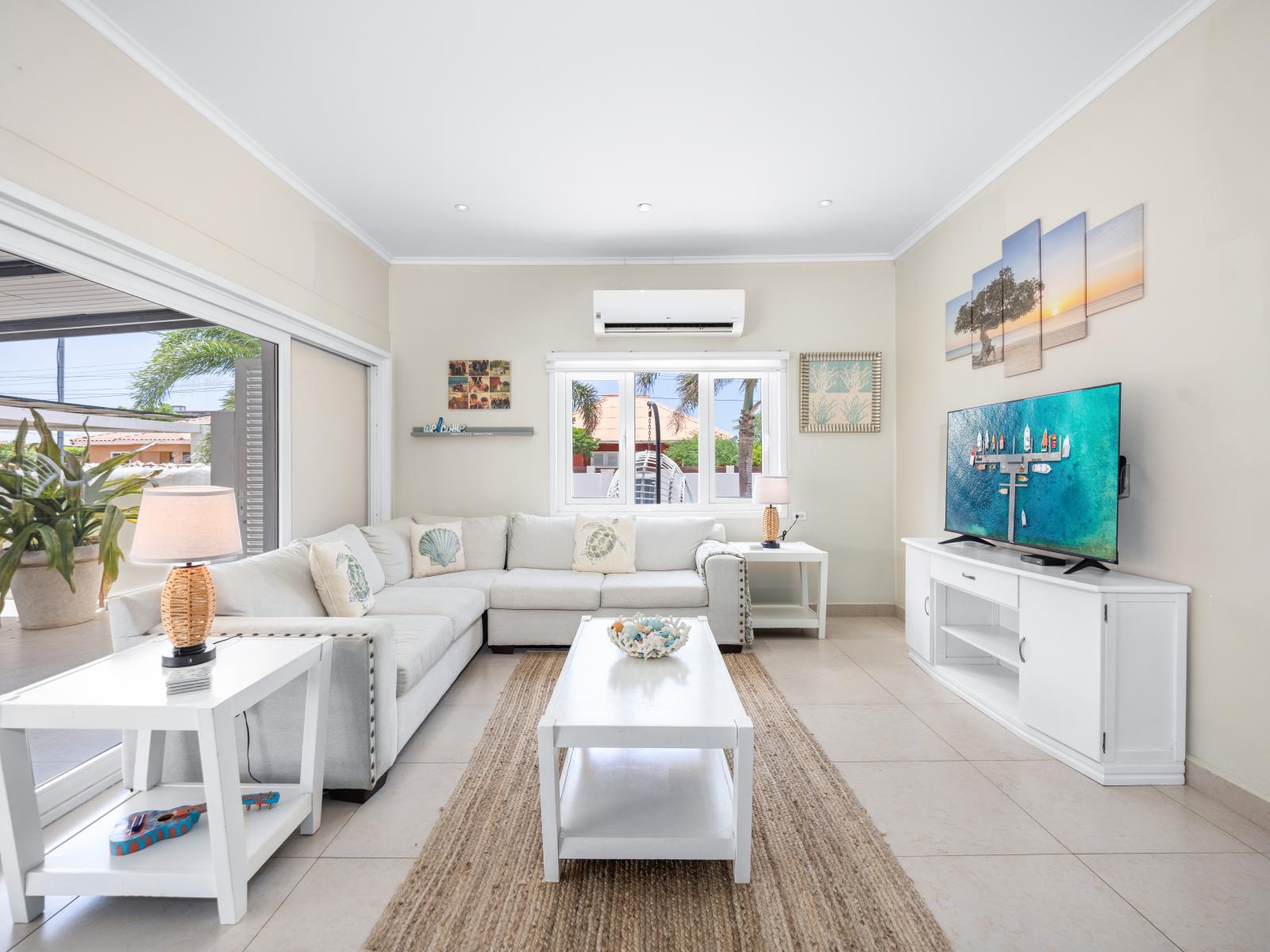 Revel in the expansive and open living area of the home in Oranjestad, Aruba - Enjoy the plush seating arrangements, perfect for lounging and unwinding - Stay entertained with a flat-screen TV and high-speed Wi-Fi, ensuring you have everything