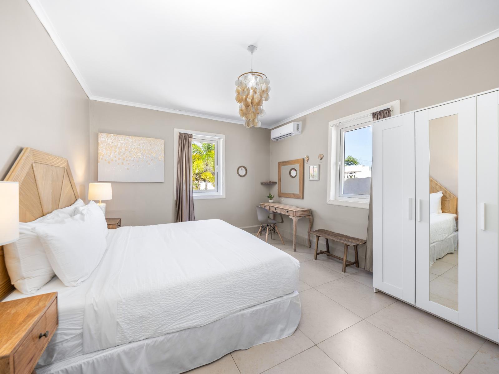 Discover the soothing color palettes of our inviting bedroom of the home in Oranjestad, Aruba - Showcasing the plush, high-quality bedding and pillows that promise a restful night's sleep - Large windows that allowing natural light to fill the room