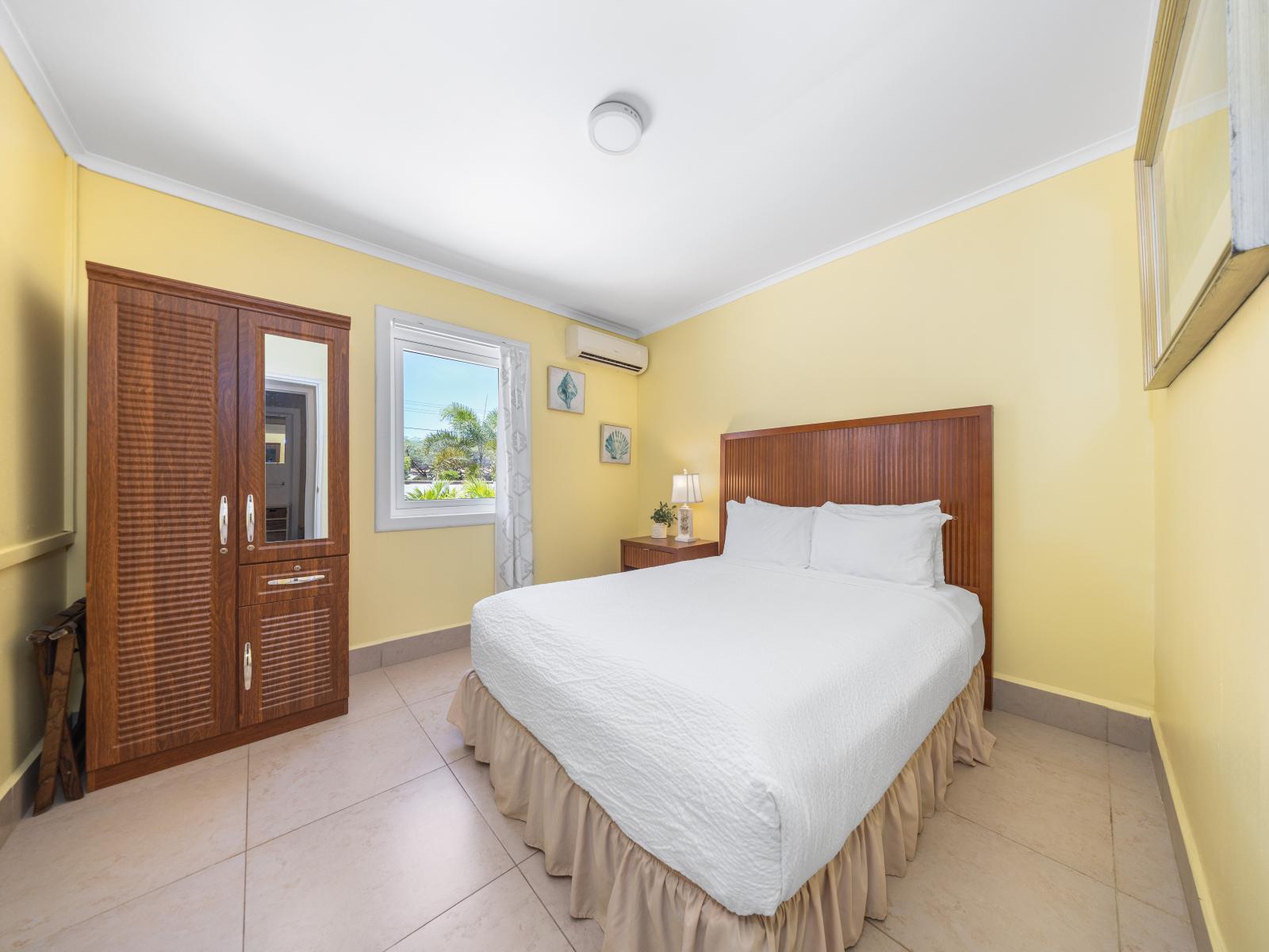 Experience the allure of this marvelous bedroom of the home in Oranjestad, Aruba - Unwind in a king-size bed outfitted with premium linens and soft  pillows - "Enjoy the charming ambiance created by soft lighting, elegant drapes and curated artwork