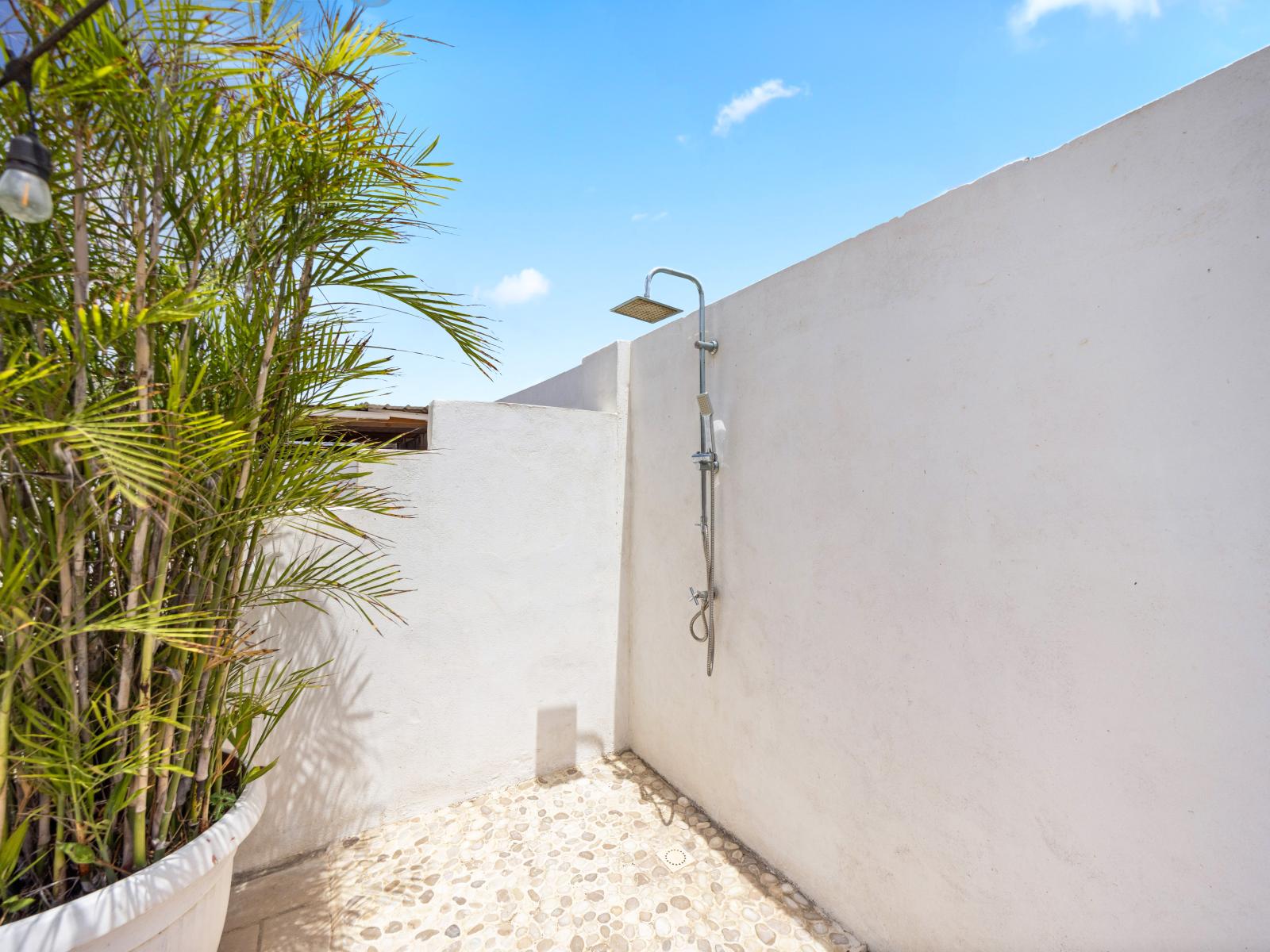 Embrace the outdoors with this nature-inspired shower area of the home in Oranjestad, Aruba - Enjoy luxurious privacy with thoughtfully designed shower area in lush surroundings - Bathe among natural elements, with stone floors and greenery