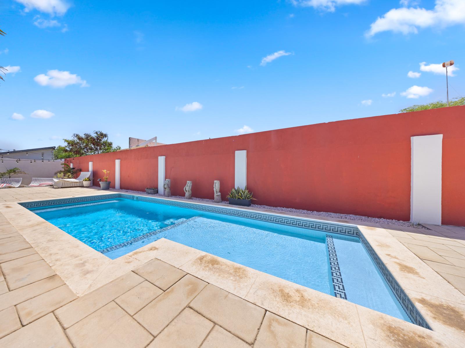 Welcome to enjoy a refreshing dip in our inviting pool of the home in Oranjestad, Aruba - Luxurious sunbeds and loungers ideal for soaking up the sun - Surrounded by lush tropical plants and beautifully manicured gardens