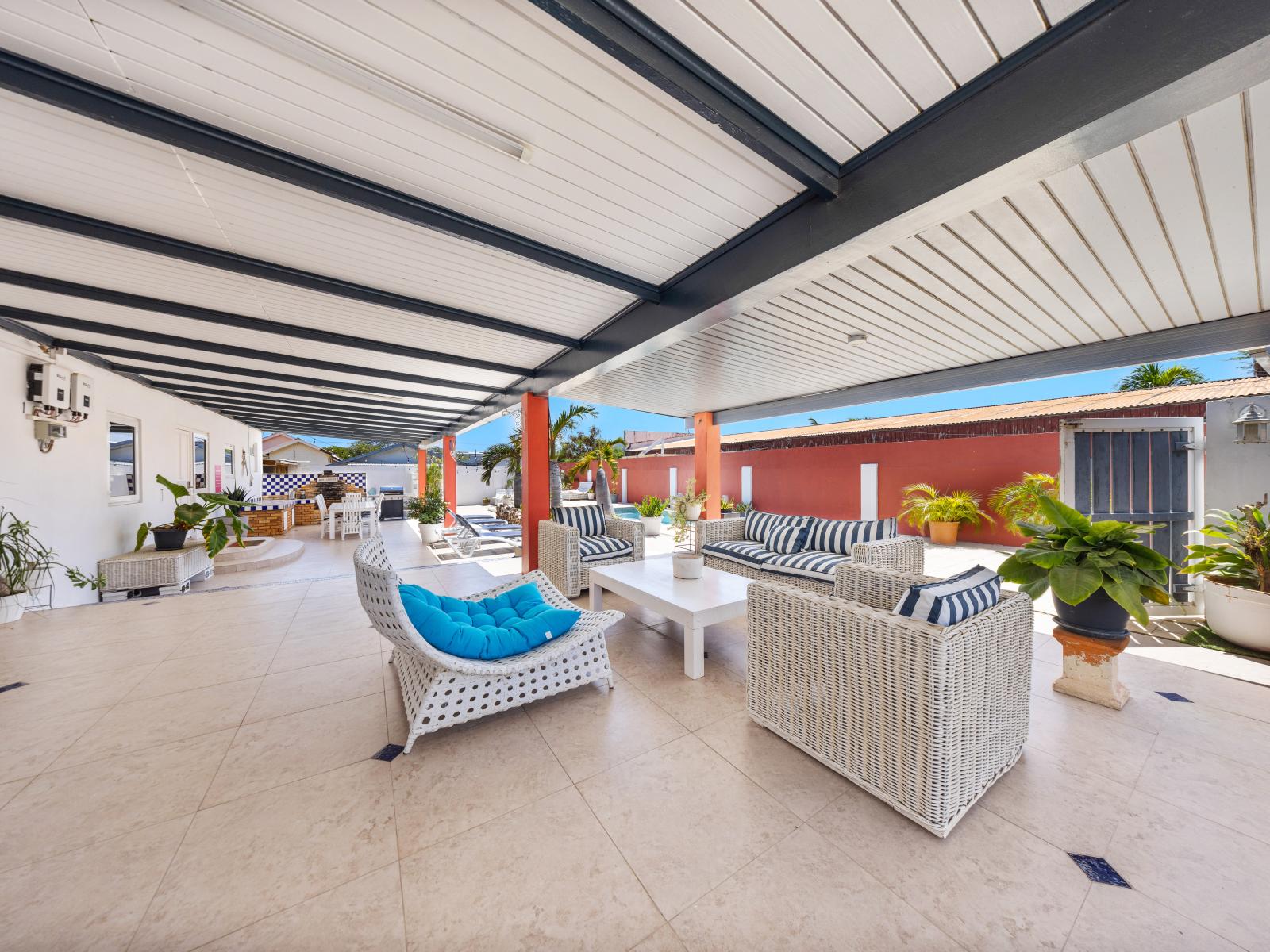 Relax in the tranquil outdoor sitting area of the home in Oranjestad, Aruba - Enjoy the comfort of plush seating sofas, perfect for lounging or reading - Plenty of  space for large groups to gather and socialize comfortably