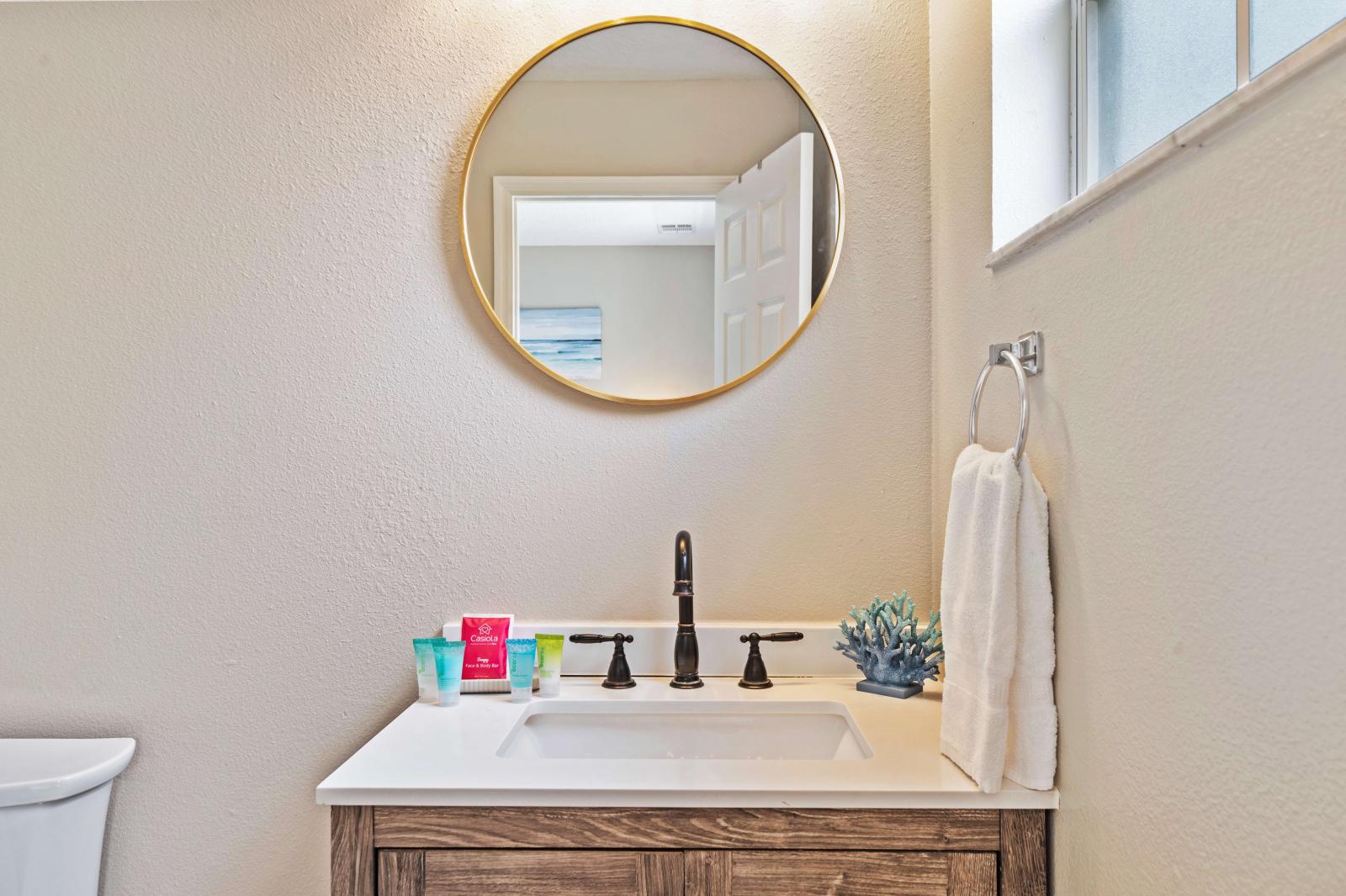 This stylish bathroom boasts a modern vanity with a beautifully framed mirror - Well-equipped with essential toiletries and plush towel, ensuring comfortable experience - Enjoy the chic decor and practical layout, designed to make you feel relaxed