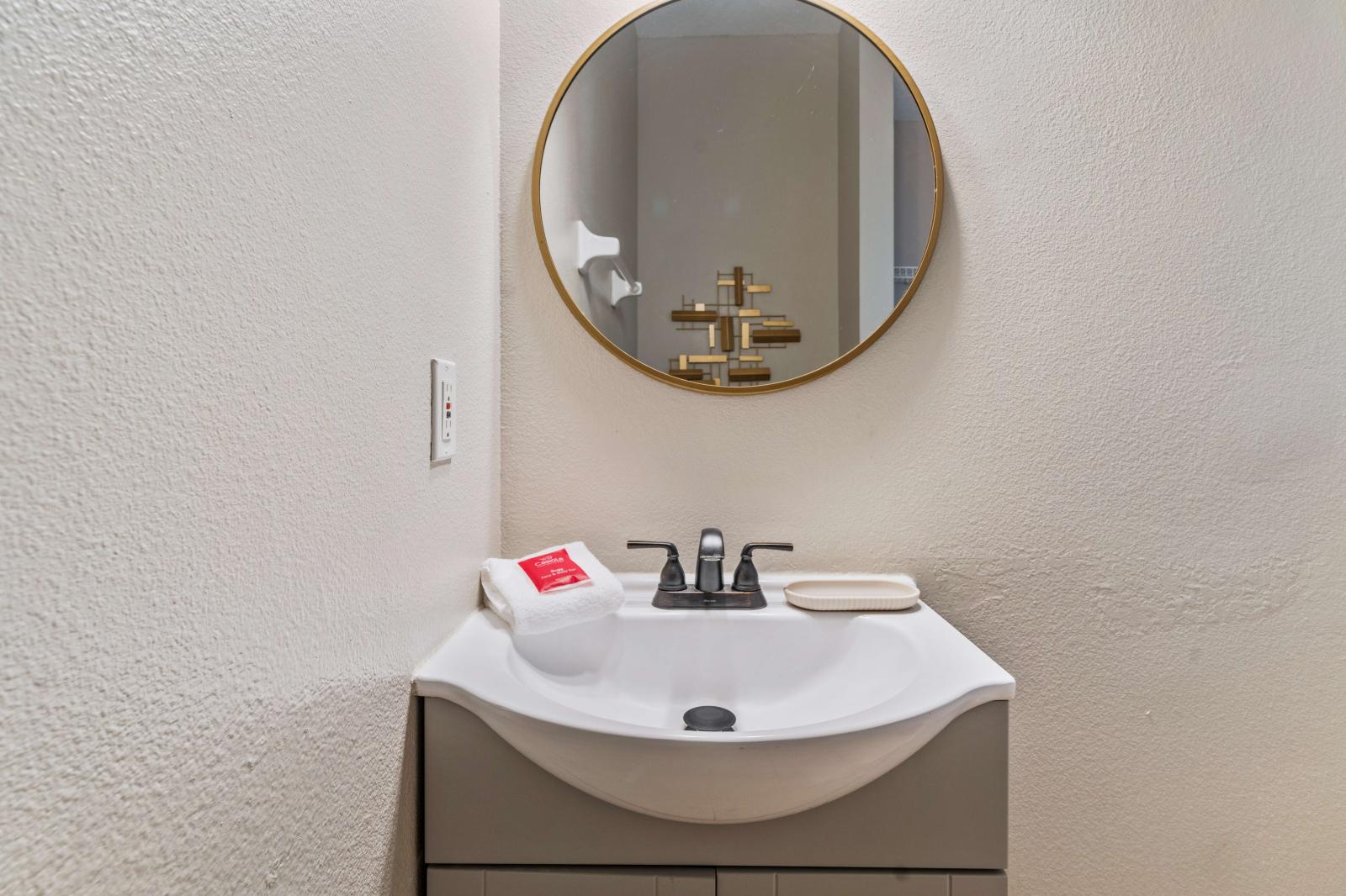 This minimalistic and stylish half-bathroom features a modern sink and vanity - Well-equipped with essential toiletries and a plush hand towel, ensuring convenience - Sleek design and practical layout, half-bathroom offers convenience and style