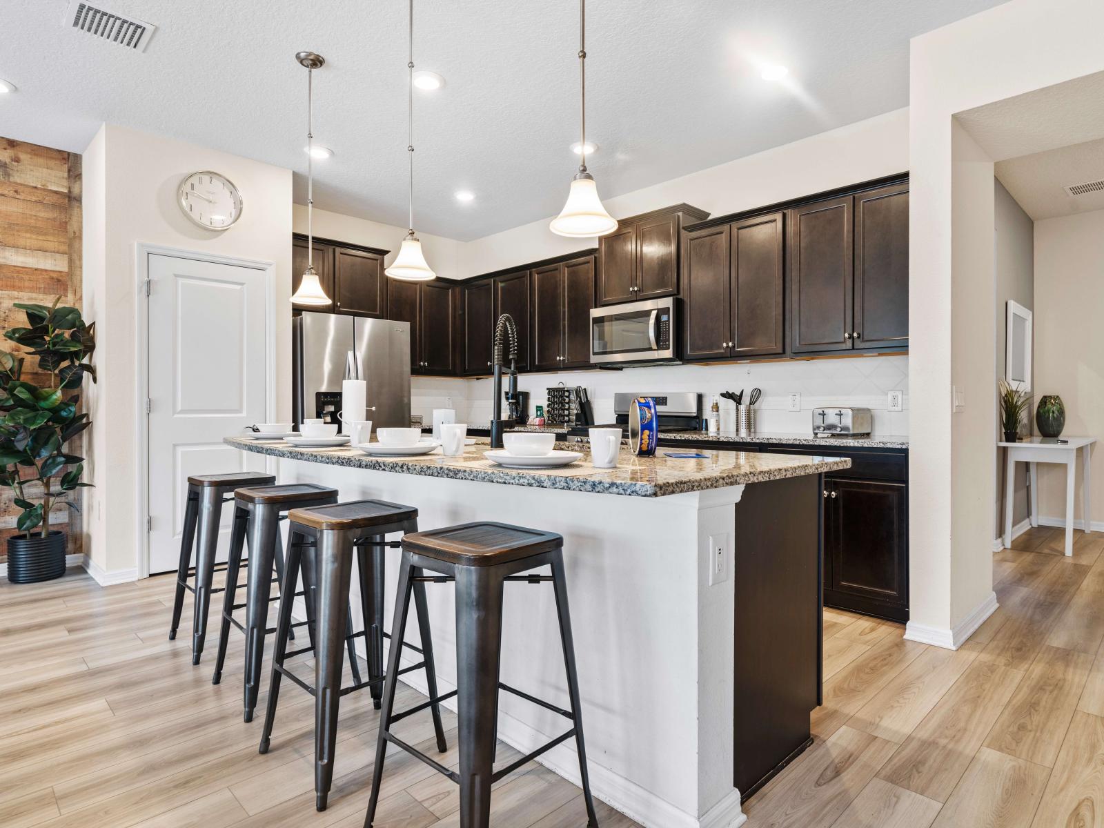 Kitchen equipped with granite countertops, and cabinet space - Elegant lighting highlights the open layout, providing a smooth transition to the living area - Spacious island with bar stools, perfect for casual meals and entertaining guests