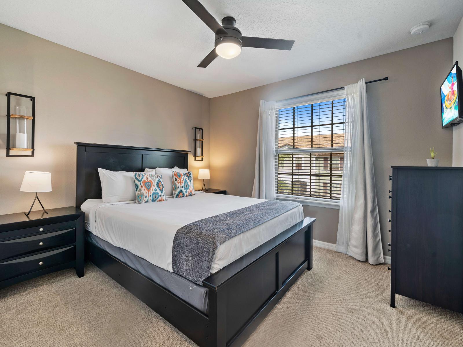 A carpeted comfortable Queen-size bedroom with stylish bedding and decorative pillows - Modern nightstands with elegant lighting and a sleek dresser for storage - A smart TV is mounted for convenient viewing, adding to the room's modern amenities