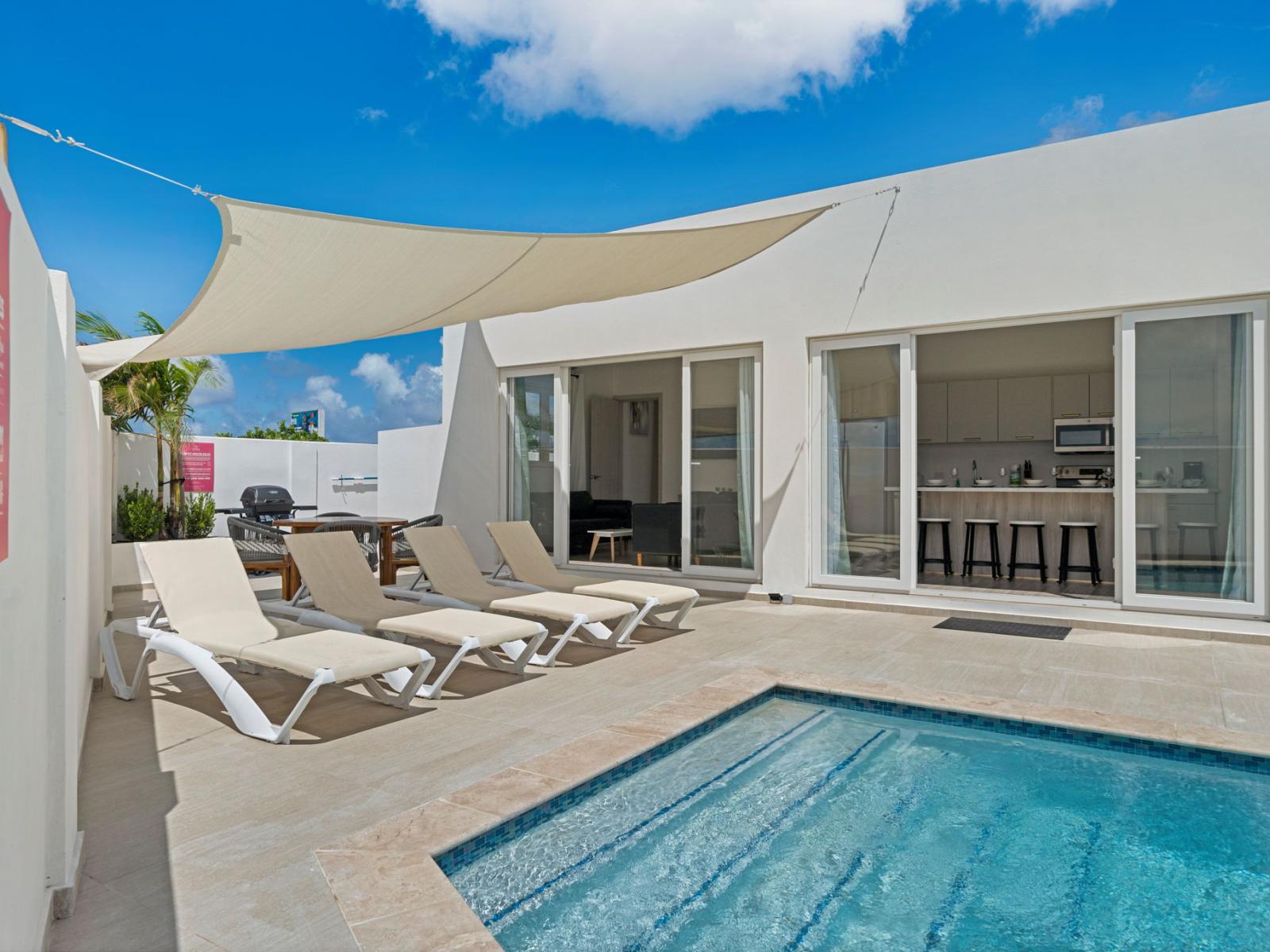 - Relax on stylish lounge chairs by the private pool, perfect for sunbathing - Enjoy seamless indoor-outdoor living with sliding doors, open to a modern kitchen - Host the perfect outdoor gathering with a BBQ grill and spacious al fresco dining setup