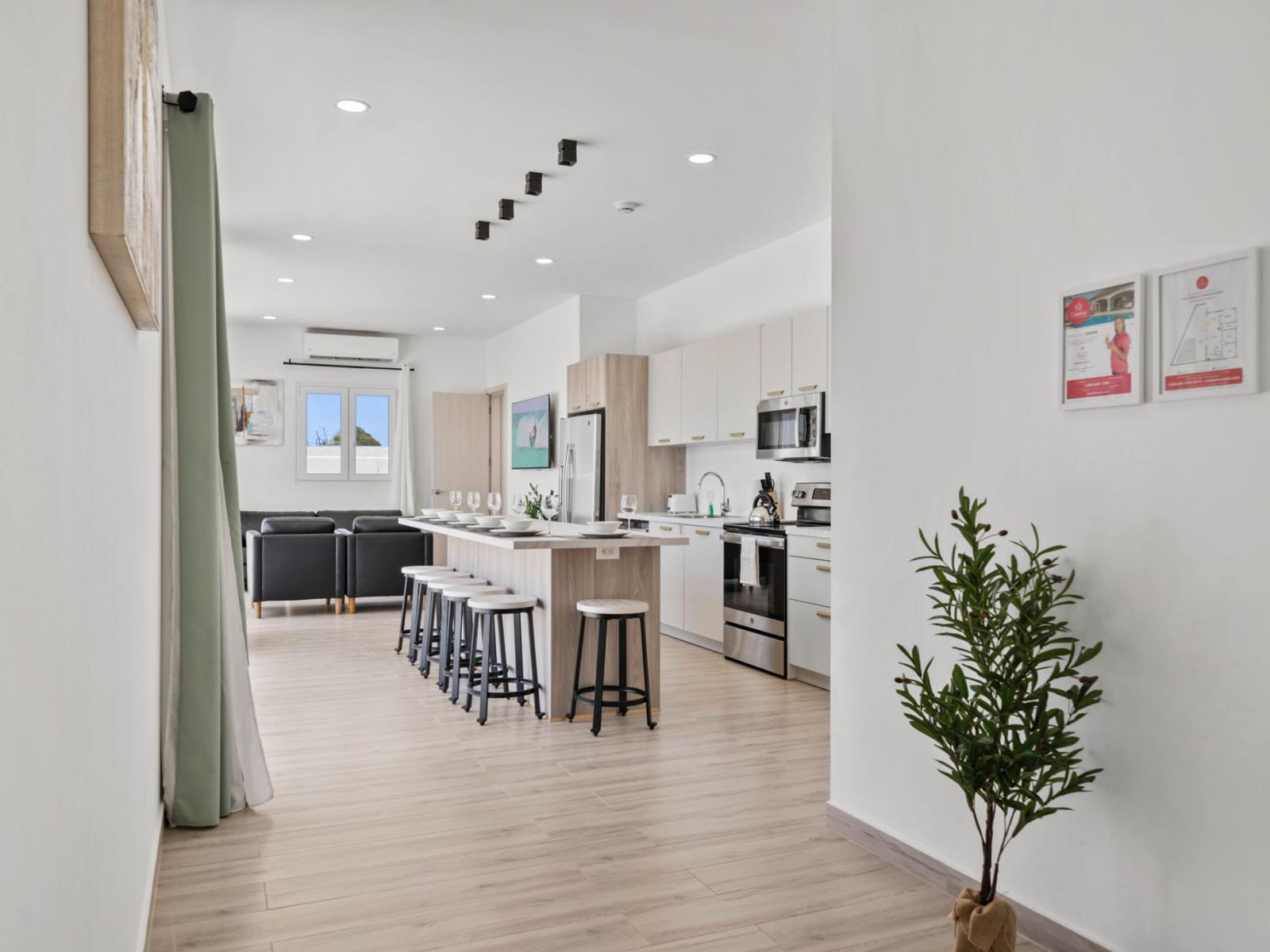 - Open-concept kitchen and living area with sleek appliances and a spacious island with barstool seating - Minimalist decor and natural light enhance the bright, airy ambiance throughout the space  - Perfect for entertaining or family gatherings