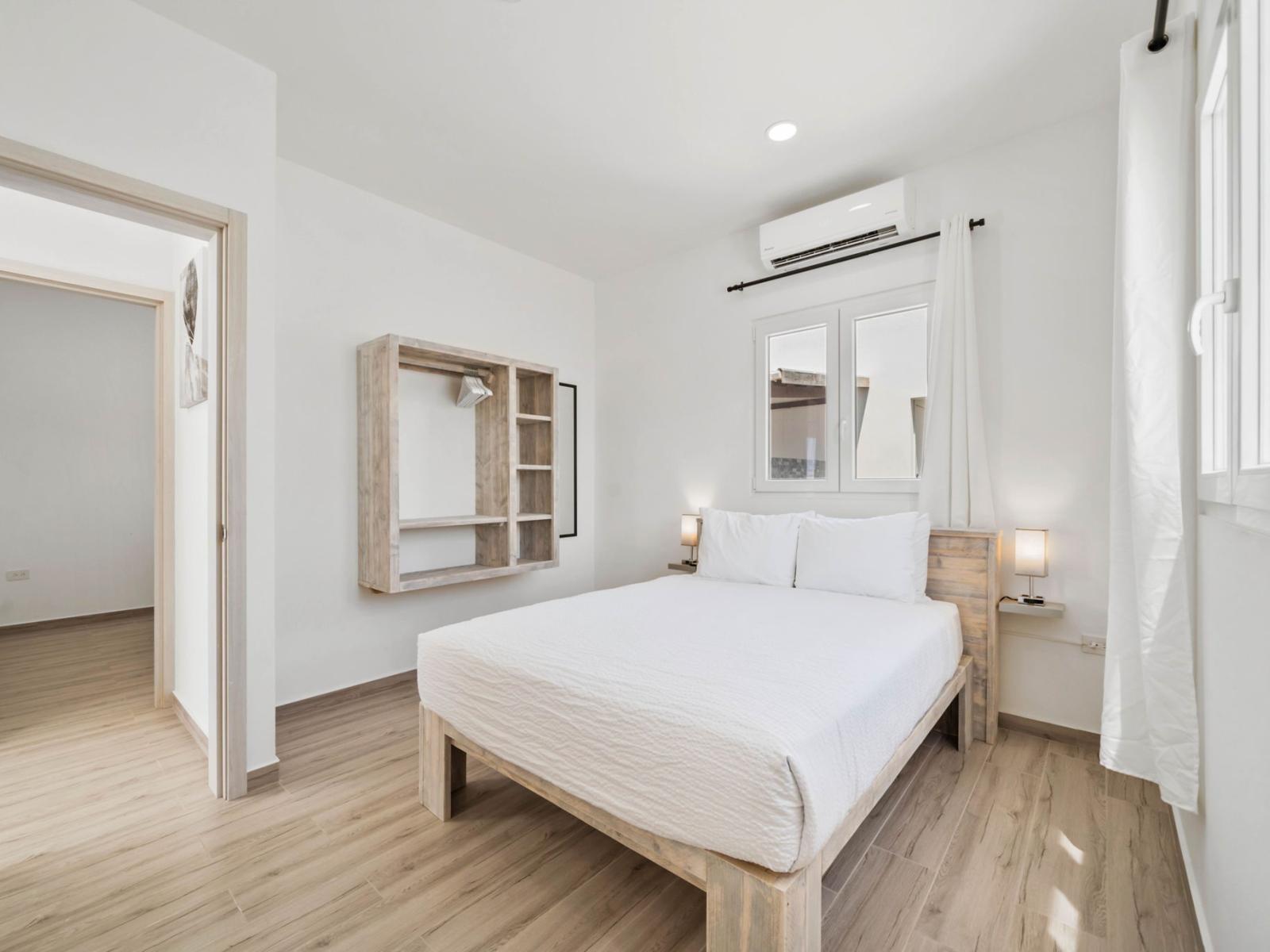 - Minimalist bedroom, featuring clean white linens for a fresh, modern look - Wall-mounted open wardrobe provides practical storage while maintaining a simple aesthetic - Soft lighting and natural light create a bright, peaceful atmosphere