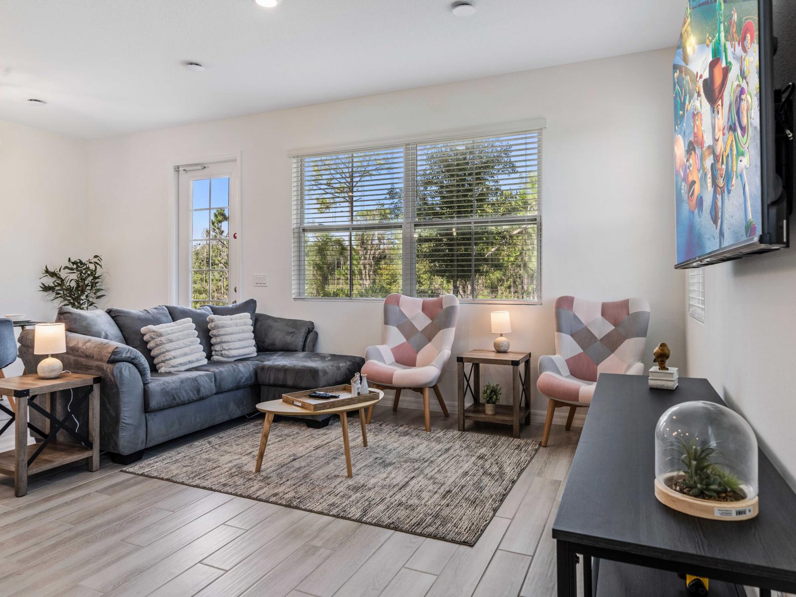 Relax in the spacious and bright living area with a cozy gray couch and large windows with views - Stylish armchairs and a coffee table for comfortable seating - Flat screen smart TV for entertainment with modern fixtures & plenty of natural light