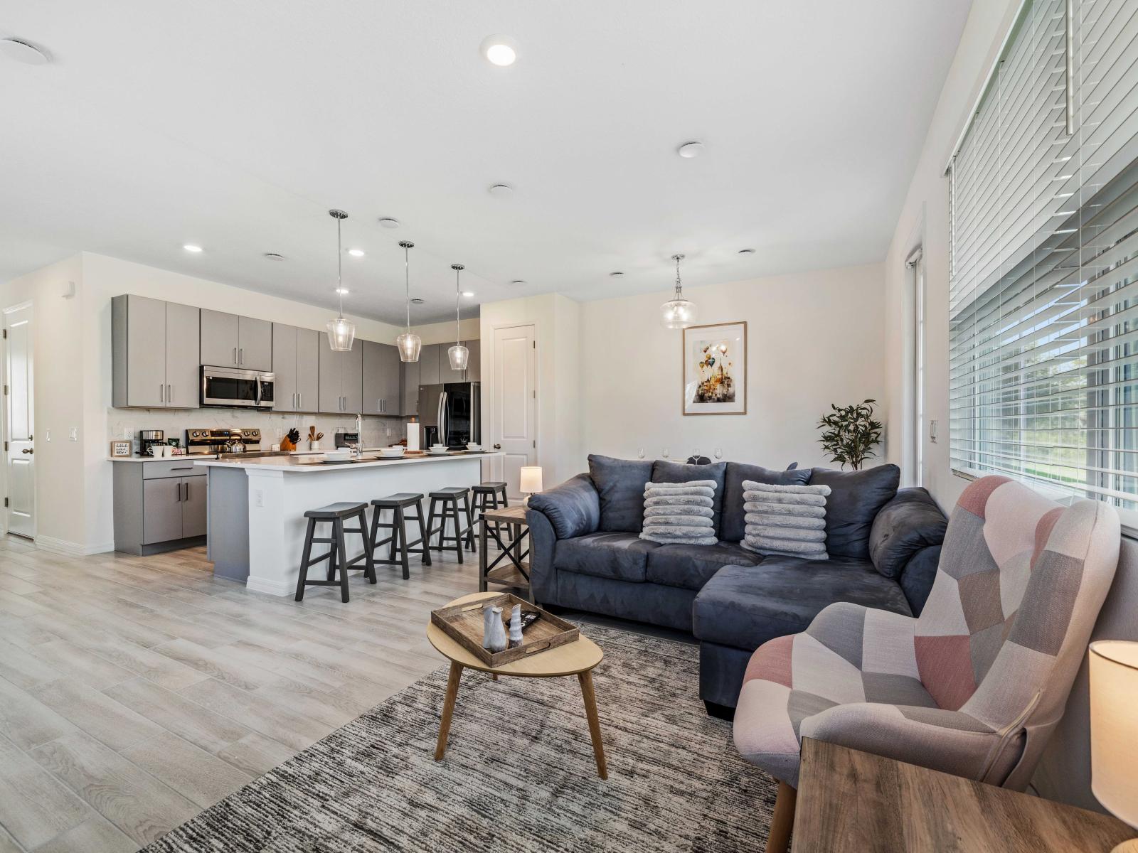 Gather with friends and family in cozy open plan living living area of the townhouse in Davenport Florida - Modern kitchen with plenty of counter space and seating - Open layout provides a seamless flow between living and dining area