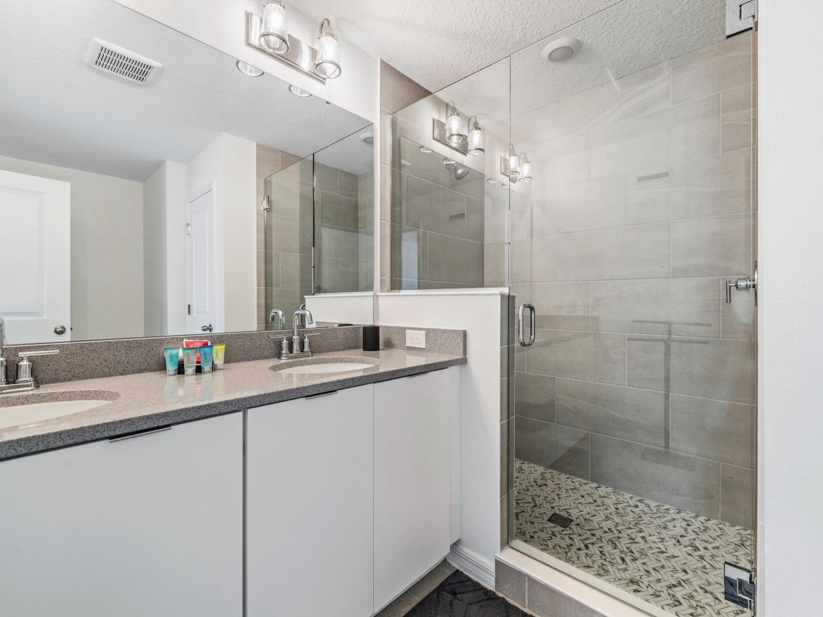 Experience the ultimate in relaxation with the soothing bathroom ambiance - Contemporary bathroom with a double vanity and sleek countertops - Large glass-enclosed shower with modern tile work and fixtures, stylish lighting and plenty storage