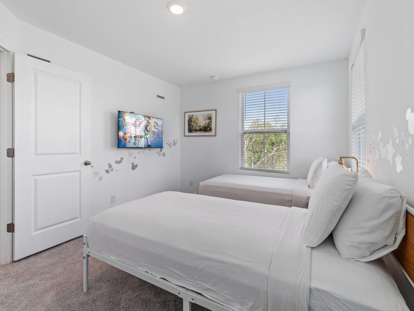 Bedroom features two comfortable single beds, perfect for children - Beautifully decorated with whimsical wall decals, adding a touch of charm to the space - Smart TV is for entertainment, and large windows provide an abundance of natural light