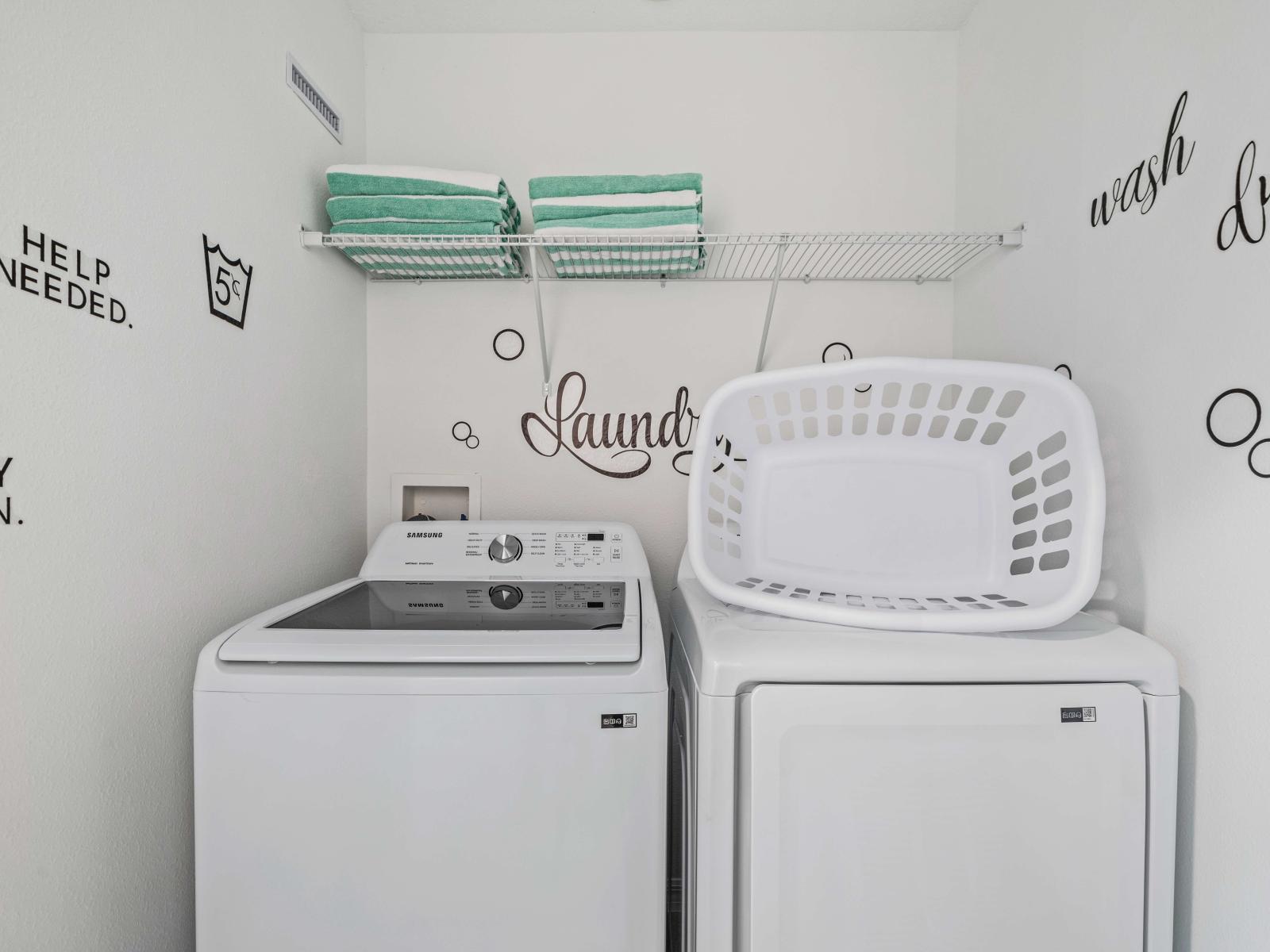 Functional laundry area equipped with washer and dryer, making laundry straightforward tasks - Shelving above appliances offers plenty of storage and organization space - Fun laundry-themed decals decorate the walls, creating a cheerful atmosphere