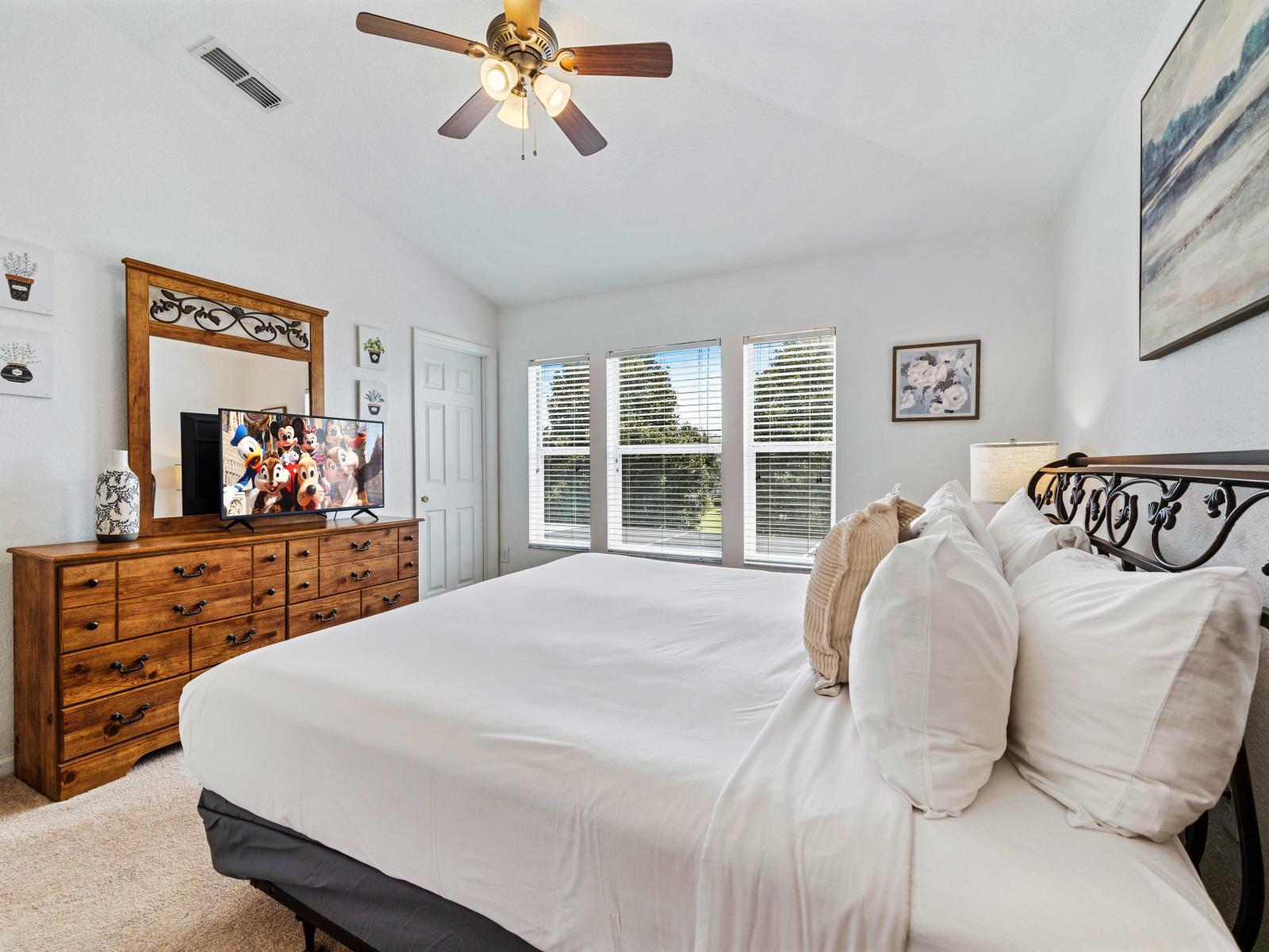 Bedroom featuring a spacious king-size bed with plush pillows and linens - Elegant wooden furniture and storage space ensure everything is neatly organized - TV for entertainment and a private bathroom for added convenience and comfort