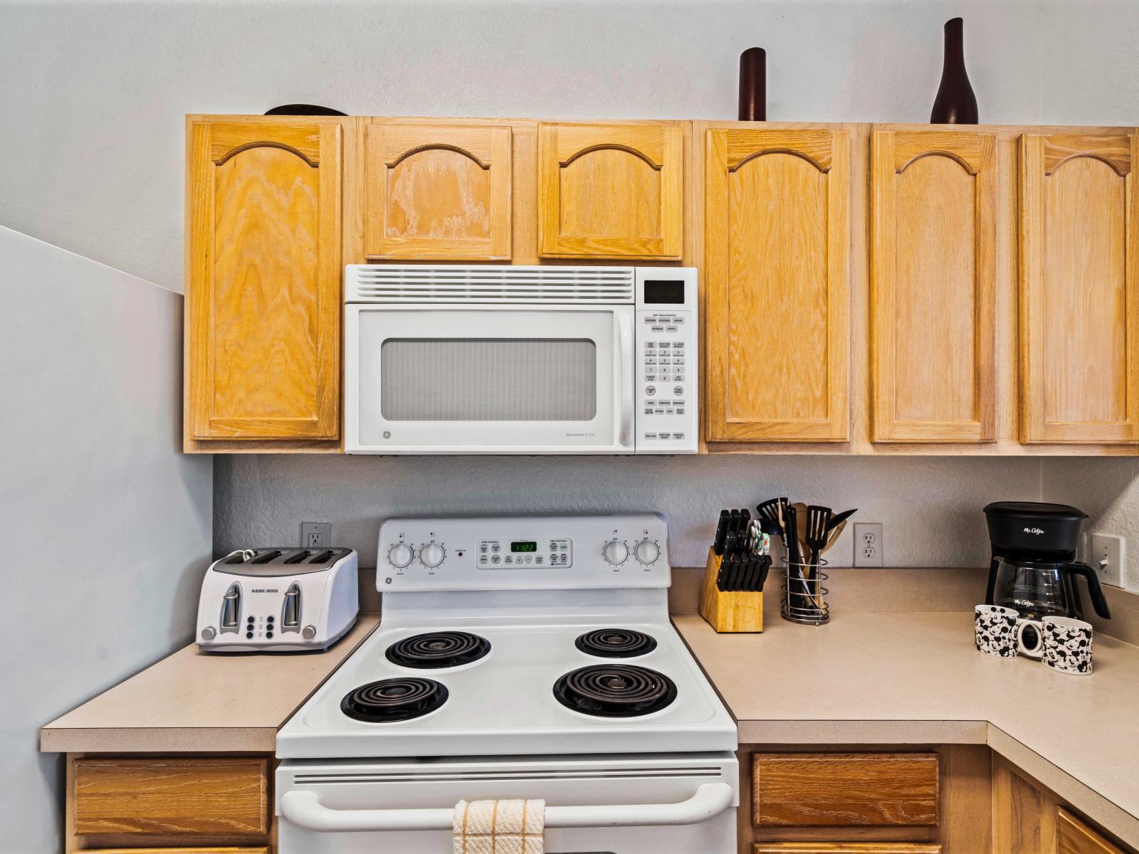 Functional kitchen corner with essential appliances: microwave, stove, and toaster - Practical countertop space for meal preparation and cooking - Wooden cabinets provide storage, complemented by a convenient coffee maker for your morning brew