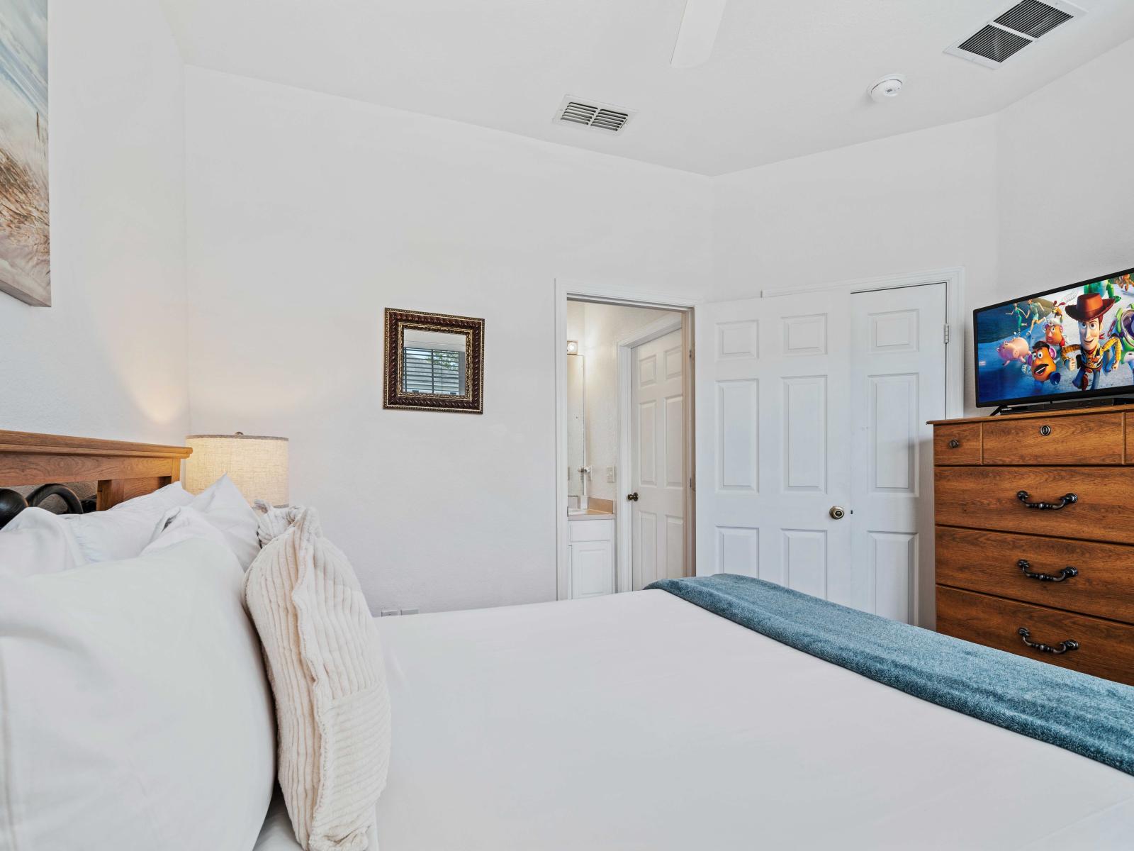 Cozy bedroom featuring a comfortable queen-size bed with plush pillows and a soft blanket - TV for entertainment and plenty of wooden storage space for convenience - Private bathroom accessible from the bedroom, ensuring privacy and comfort