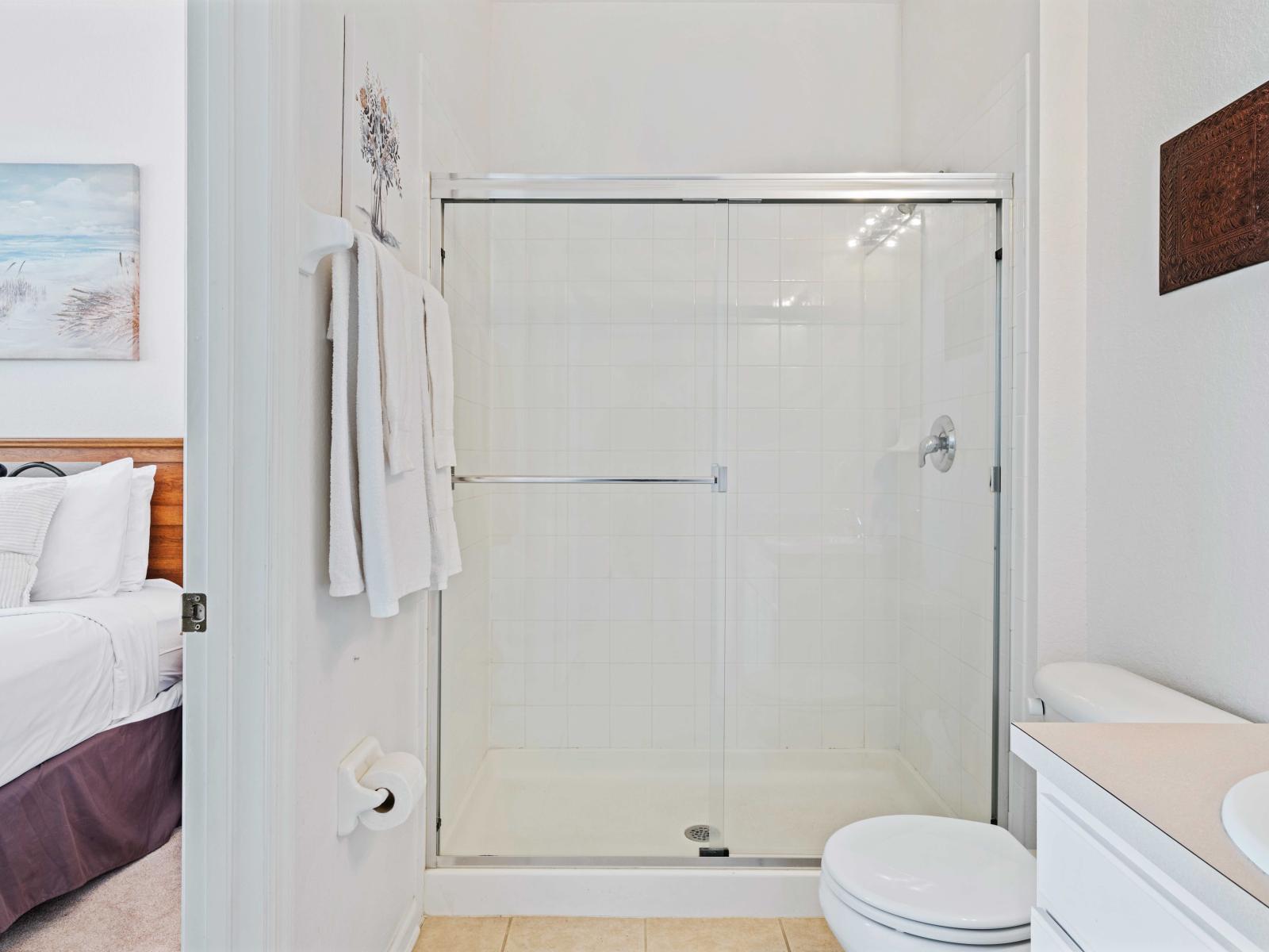 Clean and modern bathroom featuring a spacious walk-in shower with glass doors - Convenient access from the bedroom, providing privacy and ease of use - Equipped with essential amenities, including fresh towels and a well-lit vanity area