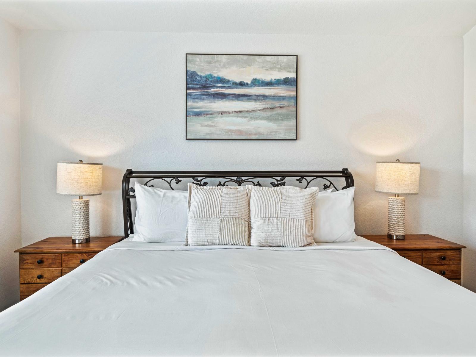 Spacious bedroom featuring a king-size bed with plush pillows and crisp linens - Warm lighting from bedside lamps creates a cozy and inviting atmosphere - Includes a private bathroom for added convenience and privacy, ensuring a comfortable stay