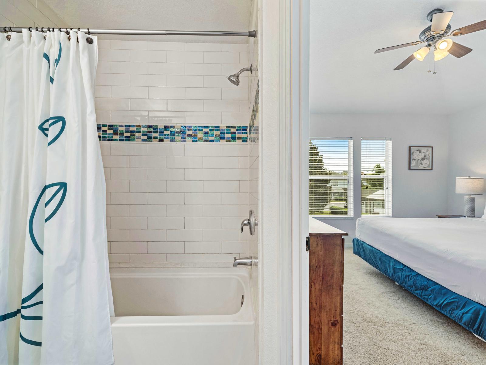 Bright and modern bathroom with a bathtub and shower combo featuring vibrant tile accents - Directly accessible from the spacious bedroom with a king-size bed - The perfect blend of comfort and convenience, offering a refreshing space to relax