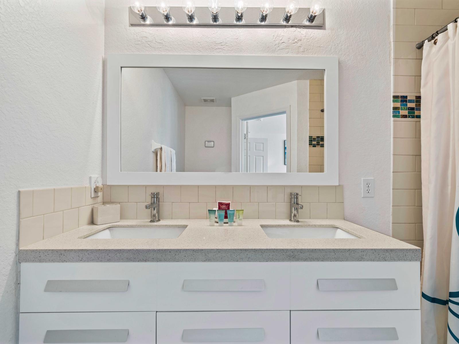 Stylish bathroom featuring a double vanity with plenty of storage and sleek countertops - Large, well-lit mirror perfect for daily grooming and getting ready - Convenient access to the adjacent bedroom, enhancing privacy and comfort for guests