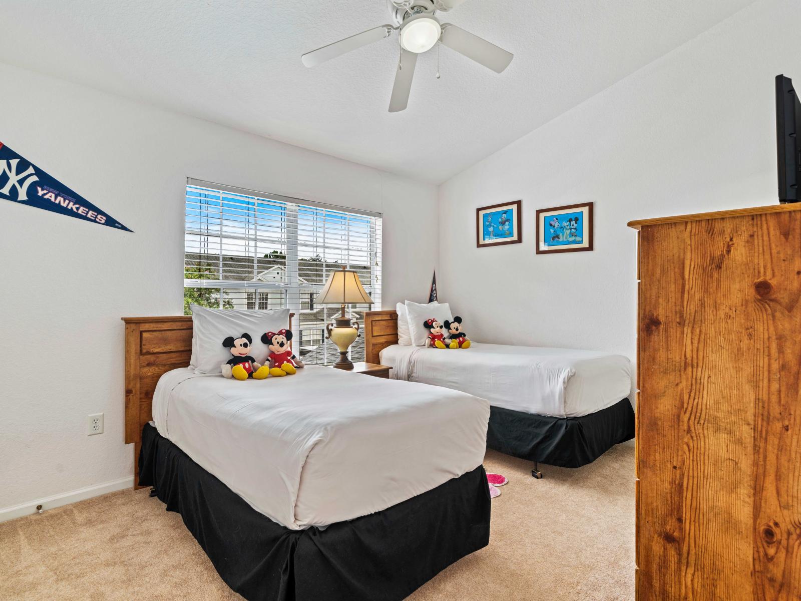 Fun and cozy bedroom featuring two single beds, perfect for kids or guests - Bright decor with Mickey Mouse plush toys and themed artwork create a playful atmosphere - Includes a private bathroom, ensuring comfort and convenience for all occupants