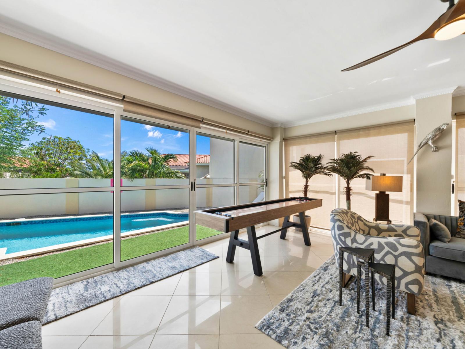 - Enjoy endless fun with a shuffleboard table in this bright sunroom overlooking the pool - Floor-to-ceiling windows invite abundant natural light, enhancing the vibrant atmosphere - Perfect blend of relaxation and entertainment in a stylish space