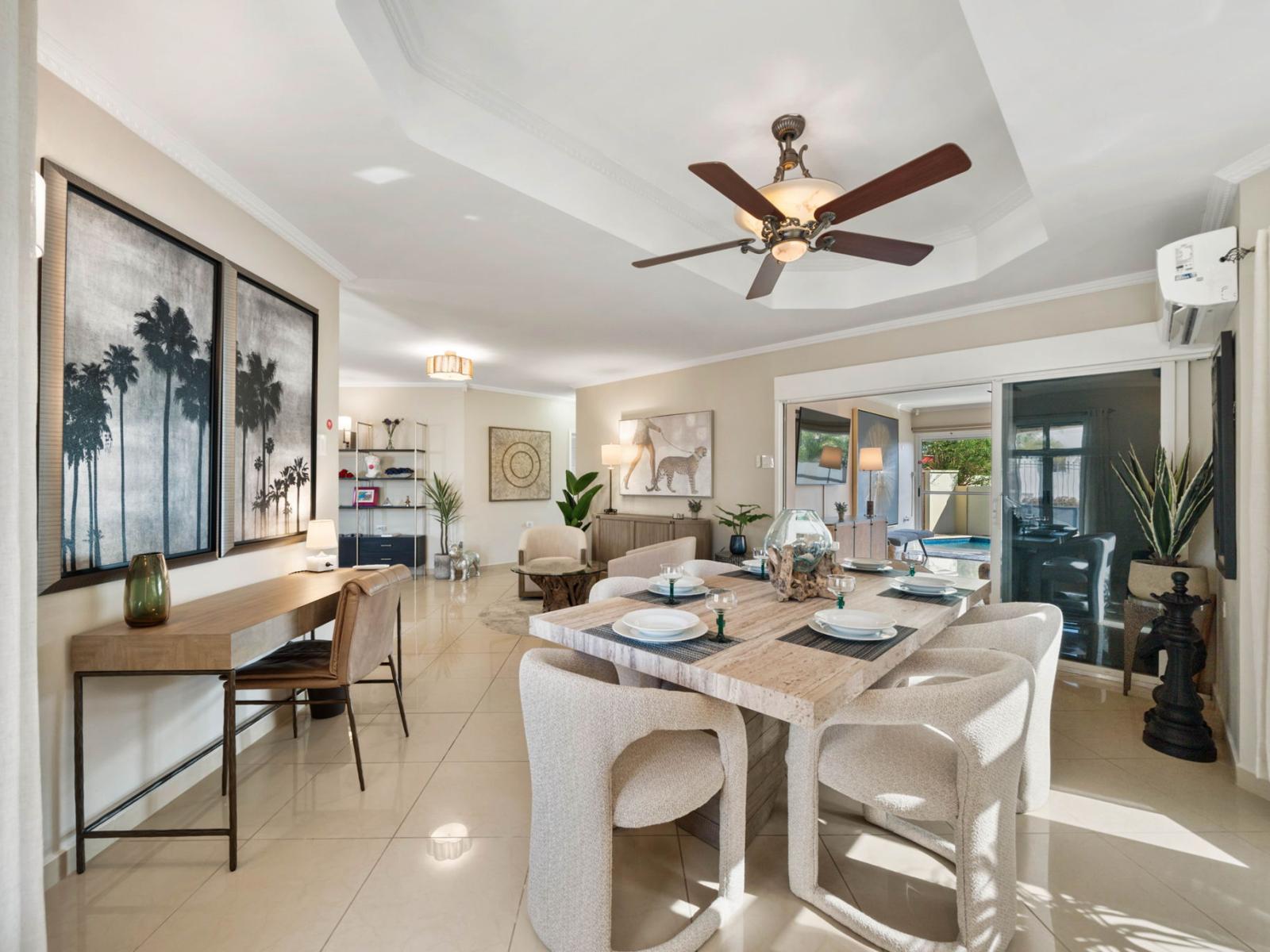 - Elegant dining area with a large wooden table, perfect for meals - Space is bright and airy, with natural light flooding in through large windows - Stylish blend of modern decor, including artwork and soft seating, creates a warm atmosphere