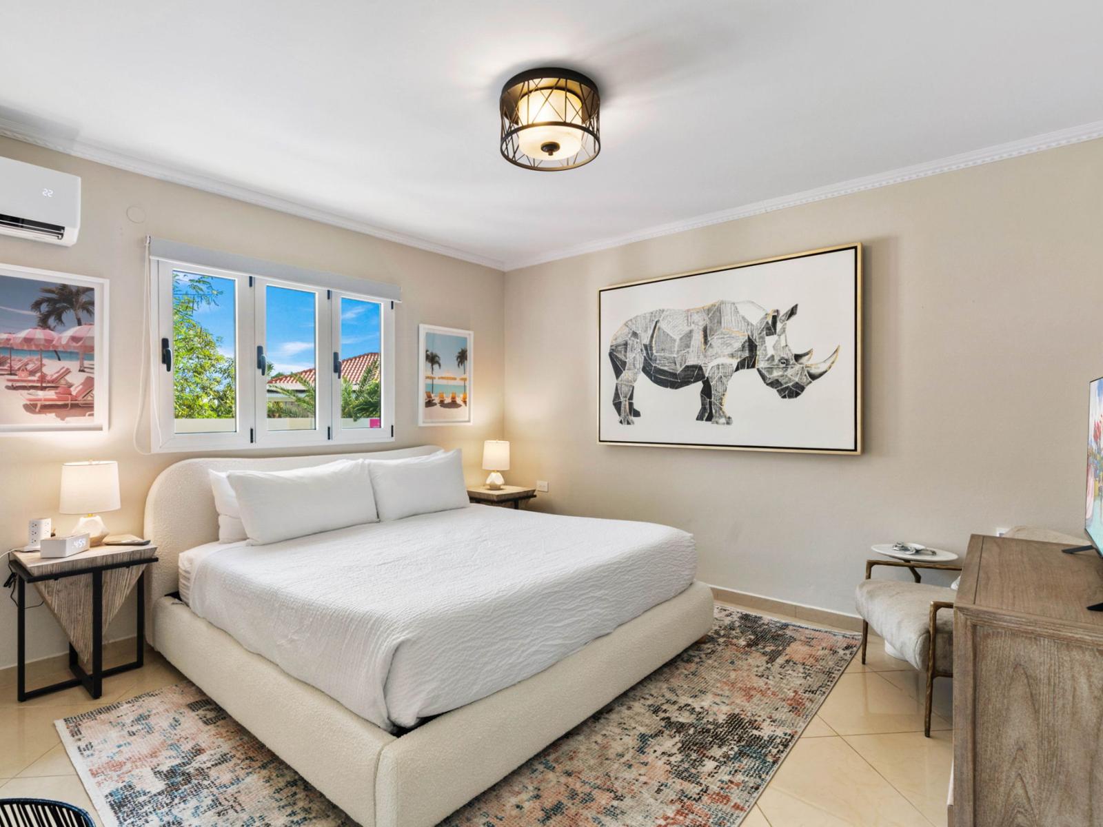 - Tranquil bedroom with a plush king-sized bed and stylish, minimalist decor - Large windows brighten the space, showcasing vibrant wall art and soft, neutral tones - A perfect retreat for restful nights, blending comfort with modern elegance