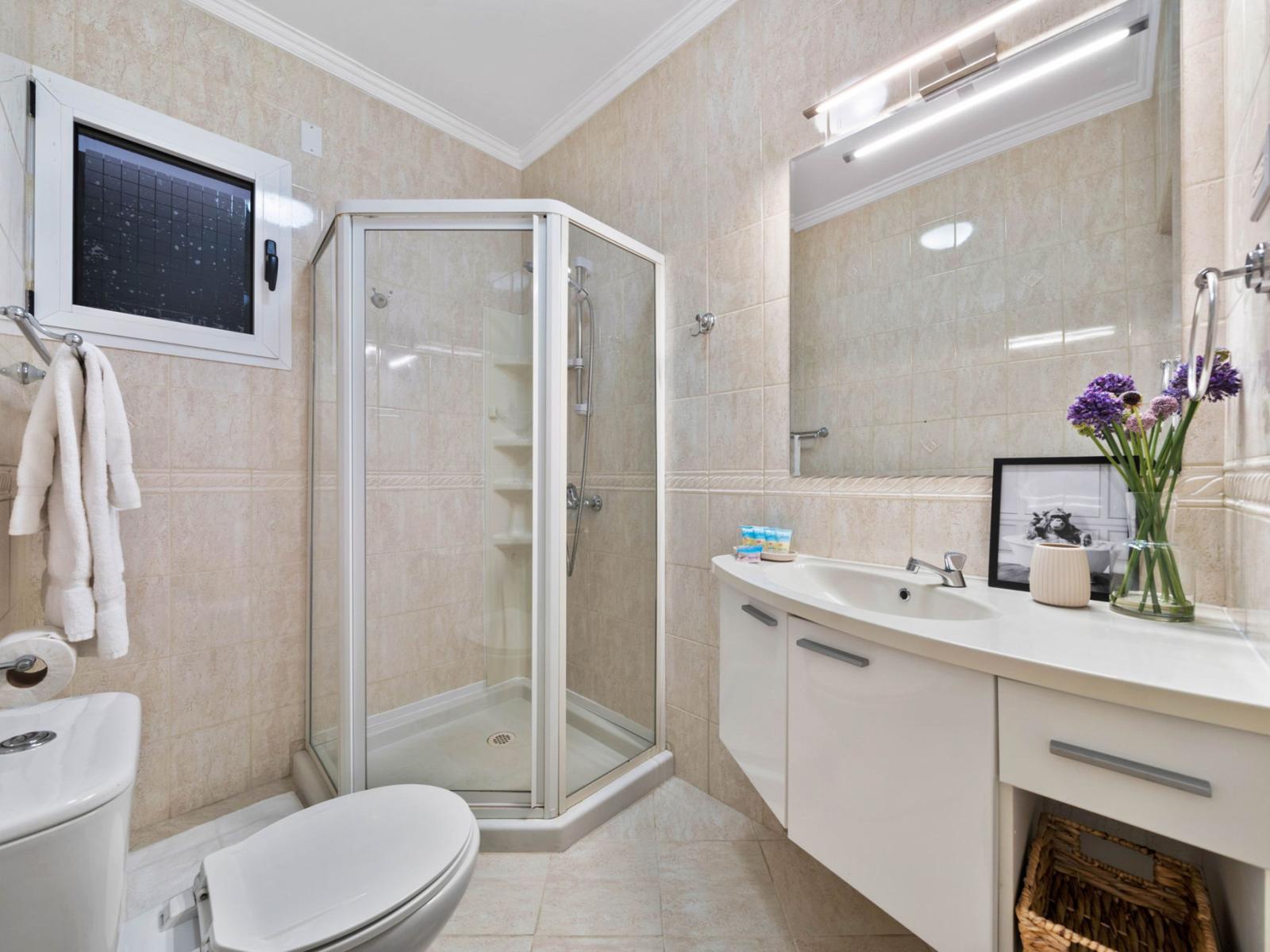 - Bright bathroom featuring a sleek corner shower and elegant white fixtures - Thoughtfully designed with counter space and soft lighting for a refreshing ambiance - Blend of style and functionality, perfect for starting or ending your day in comfort