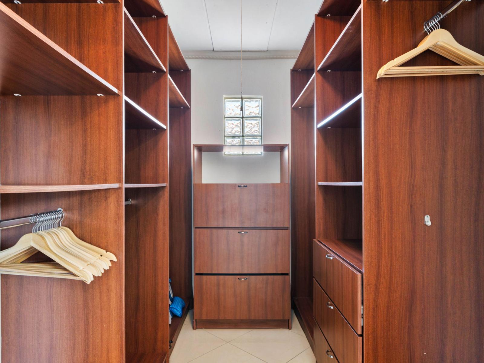 - Spacious walk-in closet with rich wooden shelving and storage space - Thoughtfully designed to keep your wardrobe organized and easily accessible - Natural light filters in, creating an inviting area for dressing and storing your essentials