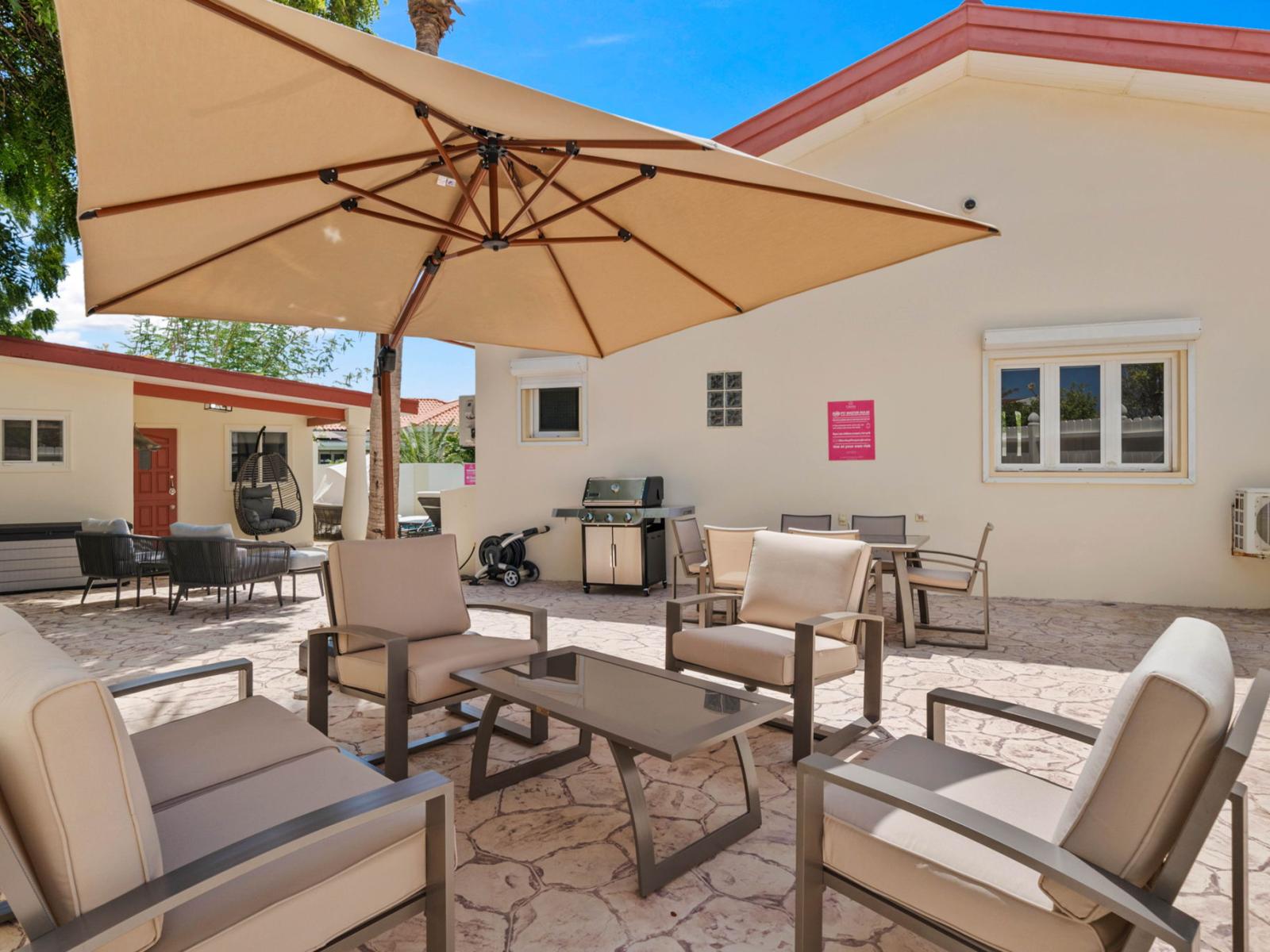 - Spacious outdoor patio with comfortable seating under a large umbrella, perfect for relaxing - Ideal setup for outdoor gatherings, with a grilling station and plenty of seating - Enjoy sunny days and cool evenings in this well-shaded space