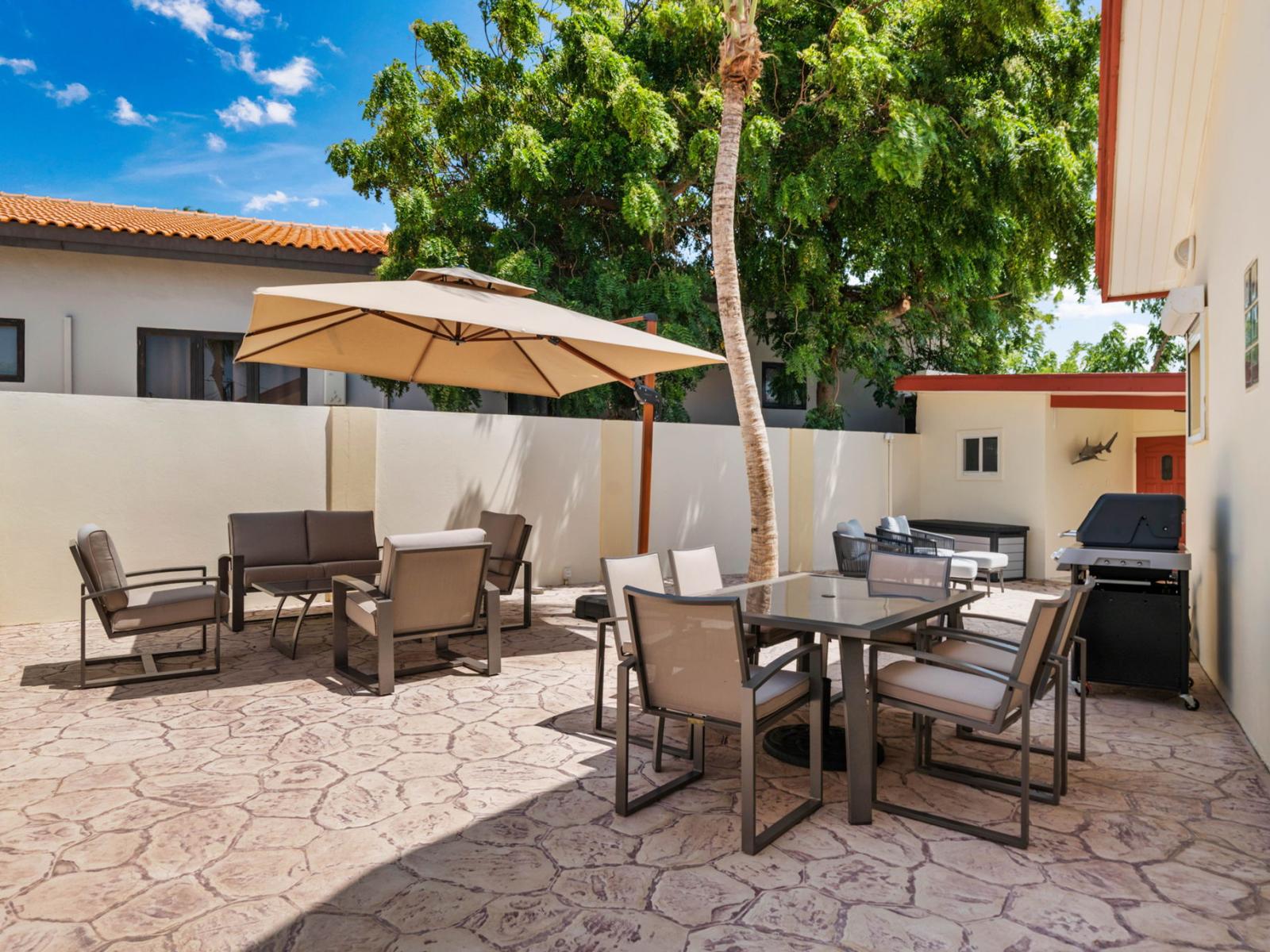 - Spacious outdoor patio with seating for dining and lounging, perfect for gatherings - Includes a large umbrella for shade and a convenient grilling station - Surrounded by greenery, it's an ideal spot for enjoying sunny days and warm evenings