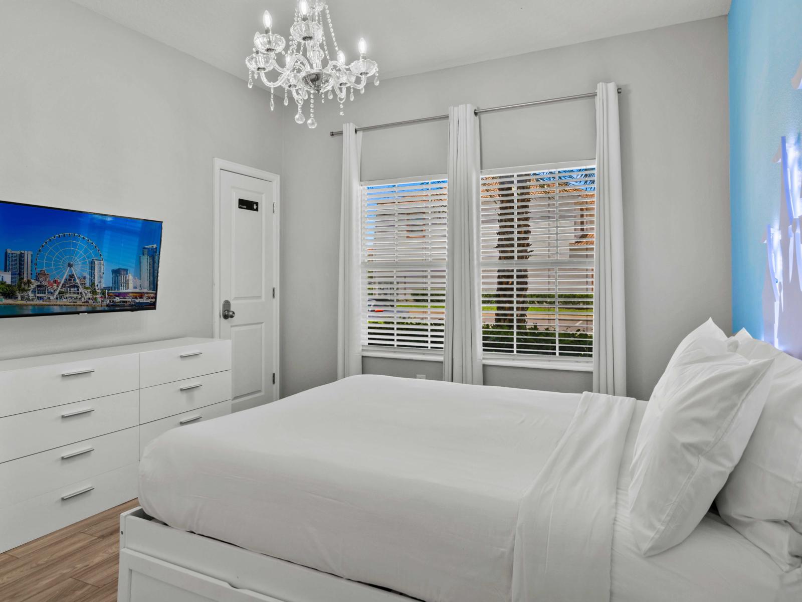 - Relax in this cozy bedroom with a plush queen-size bed, elegant chandelier, and modern flair - Bathed in natural light, space invites you to unwind with a wall-mounted TV for added comfort - A perfect blend of comfort and style for a restful stay