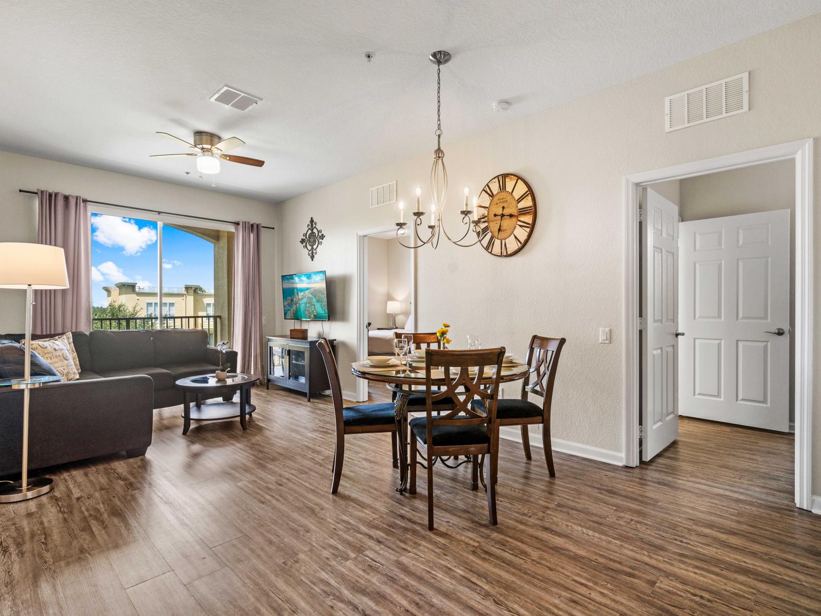 -  Living area with charming hardwood flooring &stylish decor perfect for relaxation - Enjoy meals at the elegant four-seated dining table under a charming chandelier - An airy space with large windows offering natural light & views of surroundings